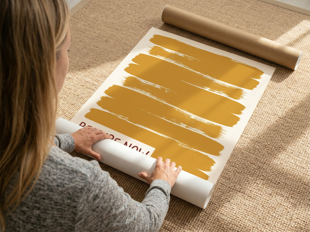 Motivational poster with yellow brushstrokes and the text Be Here Now in brown