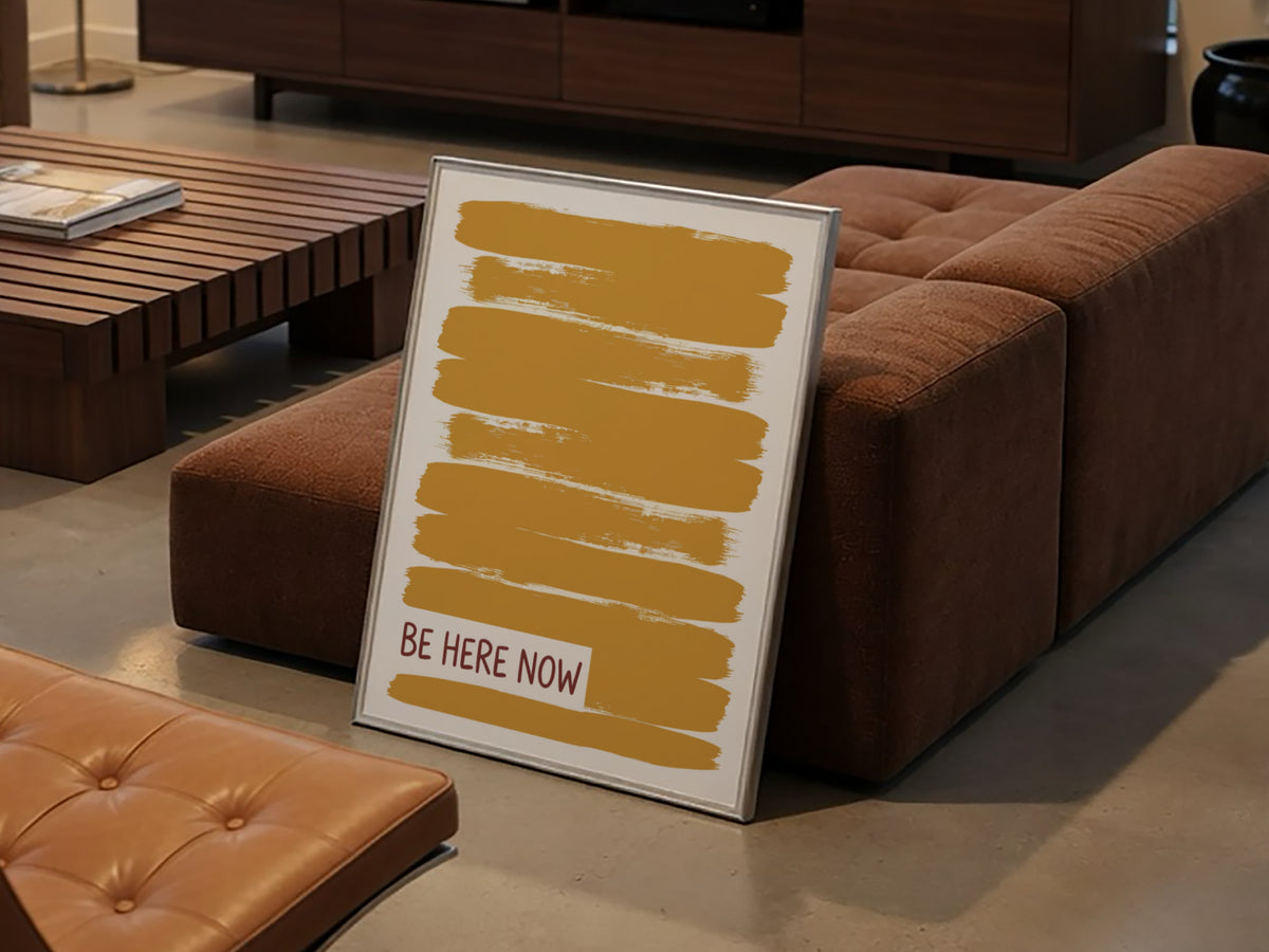 Motivational poster with yellow brushstrokes and the text Be Here Now in brown