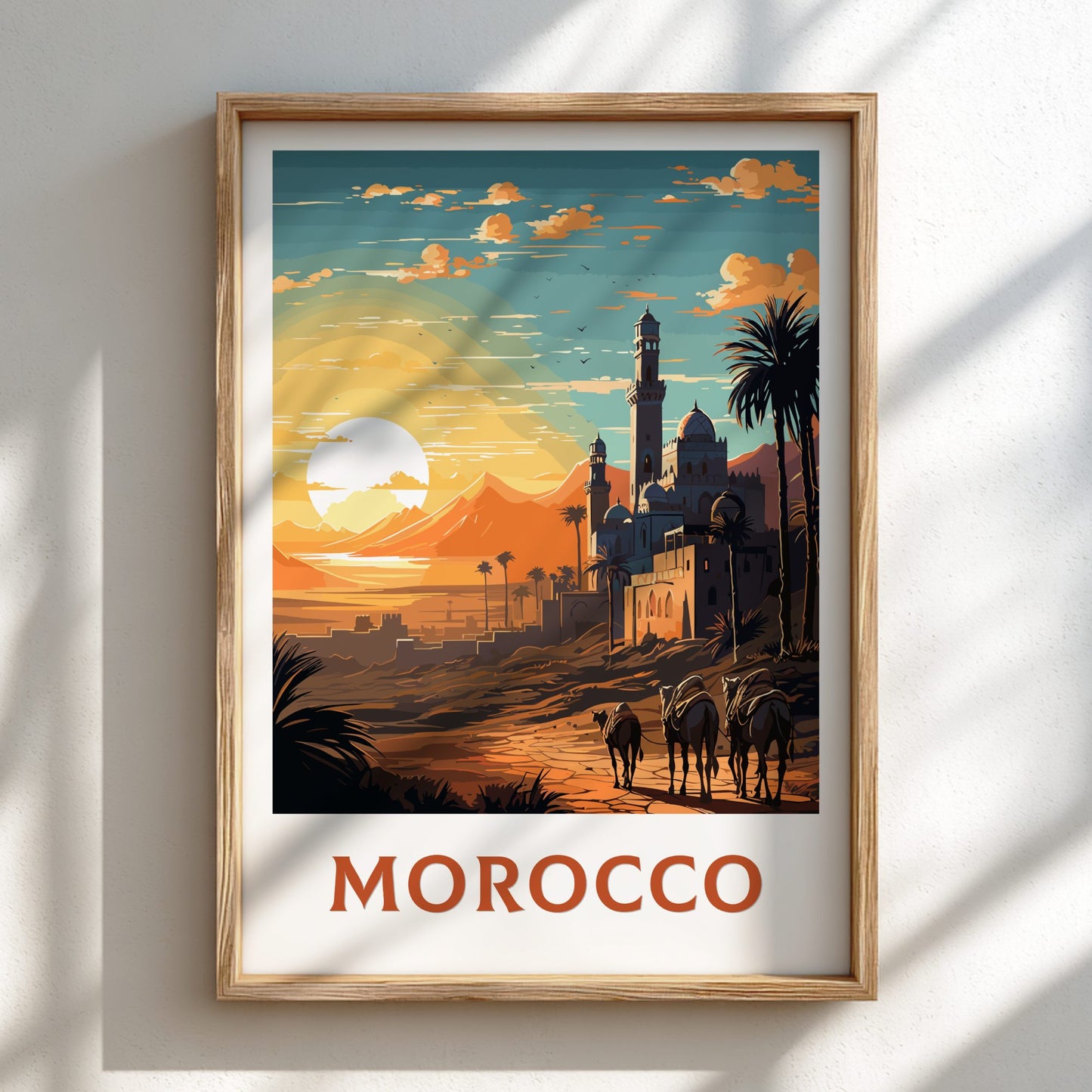 Framed artwork of a Moroccan landscape with a sunset, palm trees, and buildings.