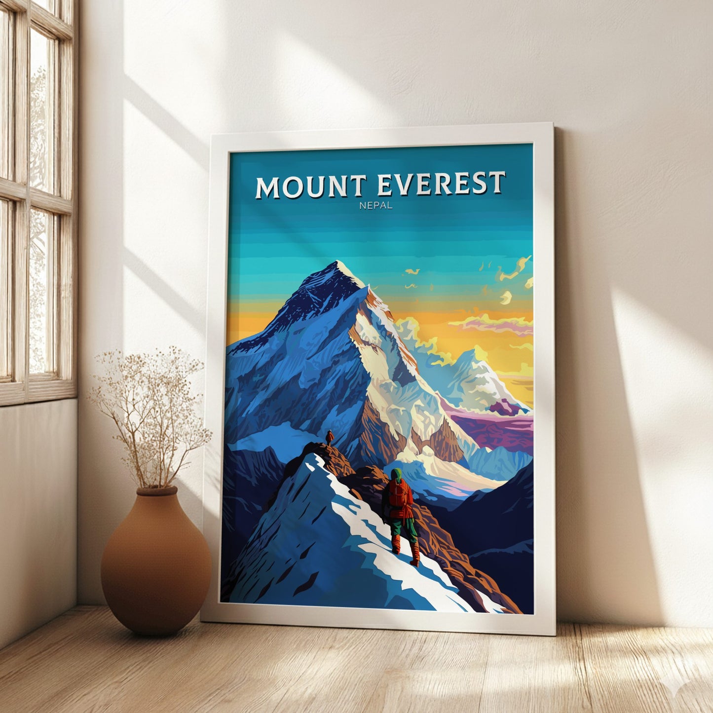 Framed poster of Mount Everest with a person climbing, placed on a wooden floor with a vase beside it.