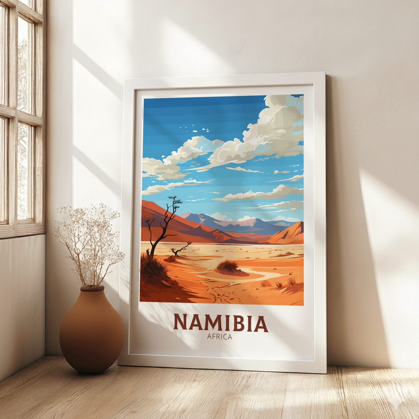 Framed poster of a desert landscape with 'Namibia, Africa' text in a room with a vase and window.