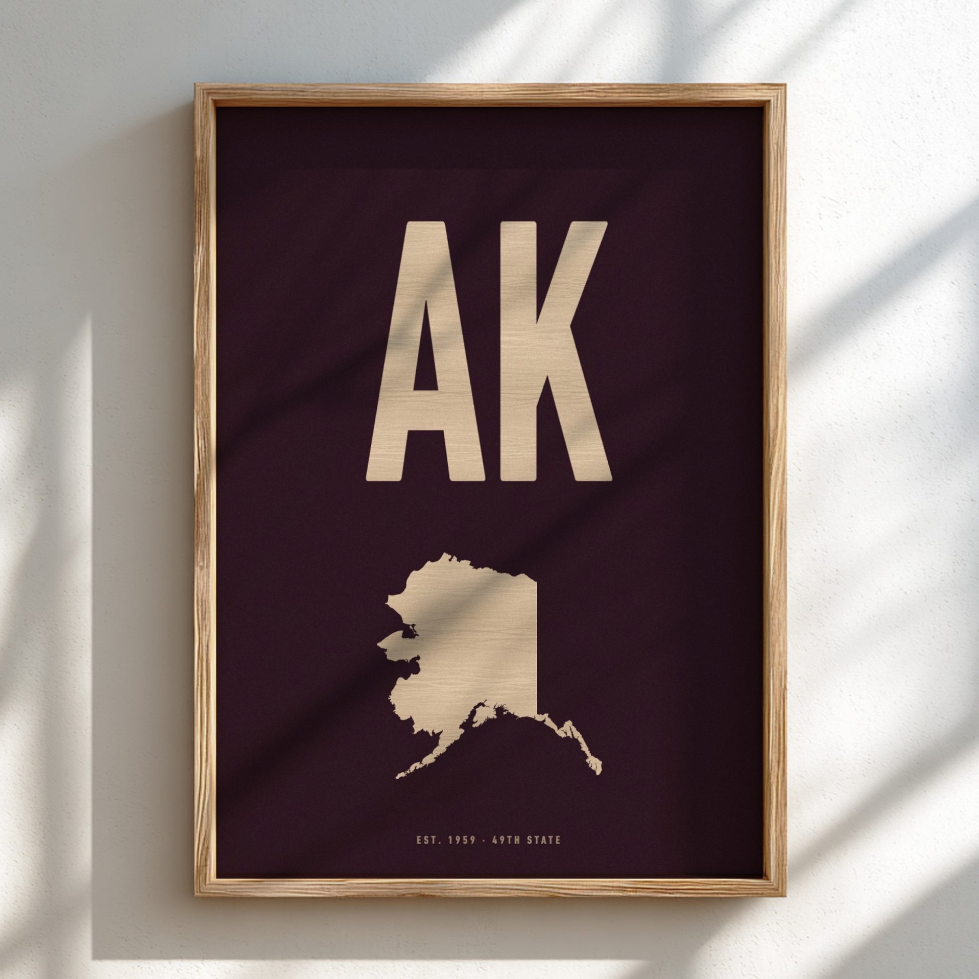 Framed artwork with 'AK' and outline of Alaska on a dark background