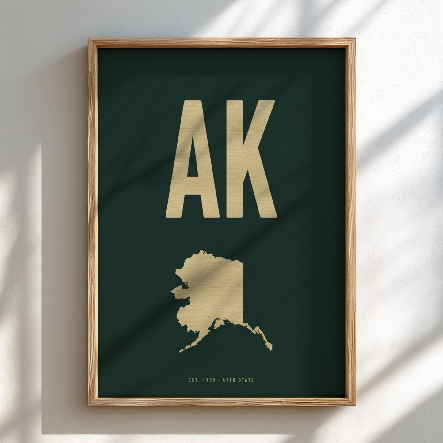 Framed artwork with 'AK' and a map of Alaska on a dark green background