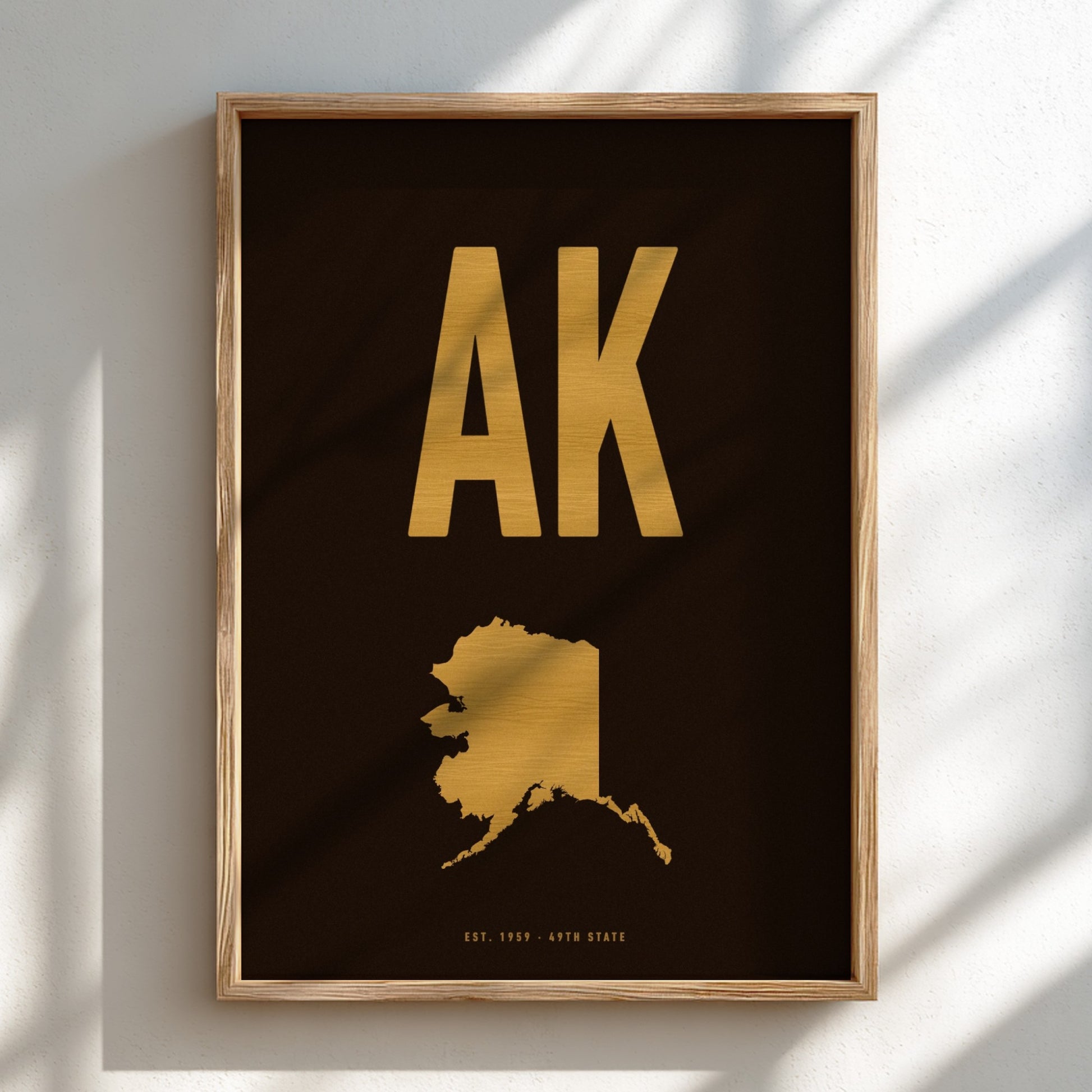 Framed artwork with gold 'AK' and state outline on a black background