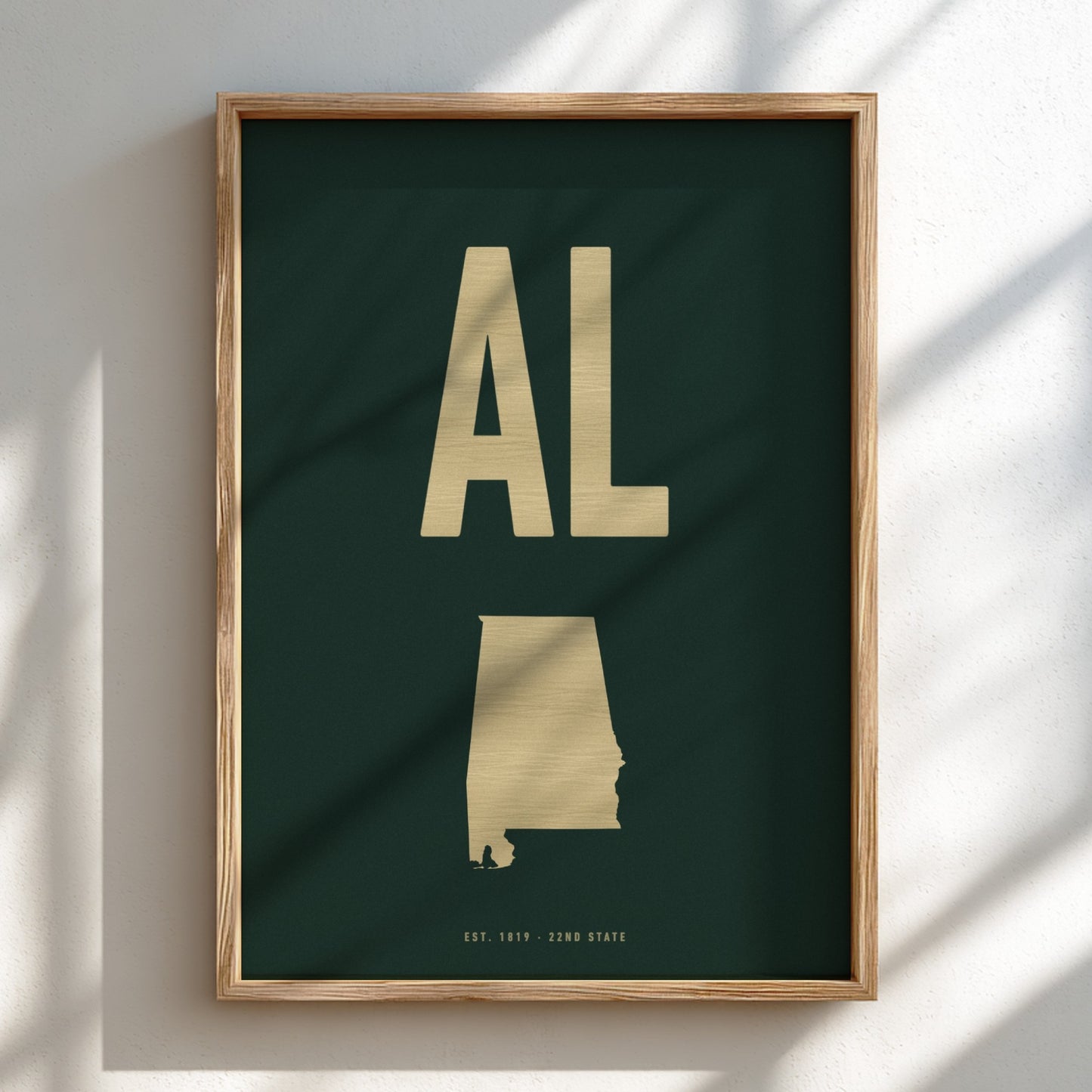 Framed poster with gold 'AL' and state outline on a dark green background