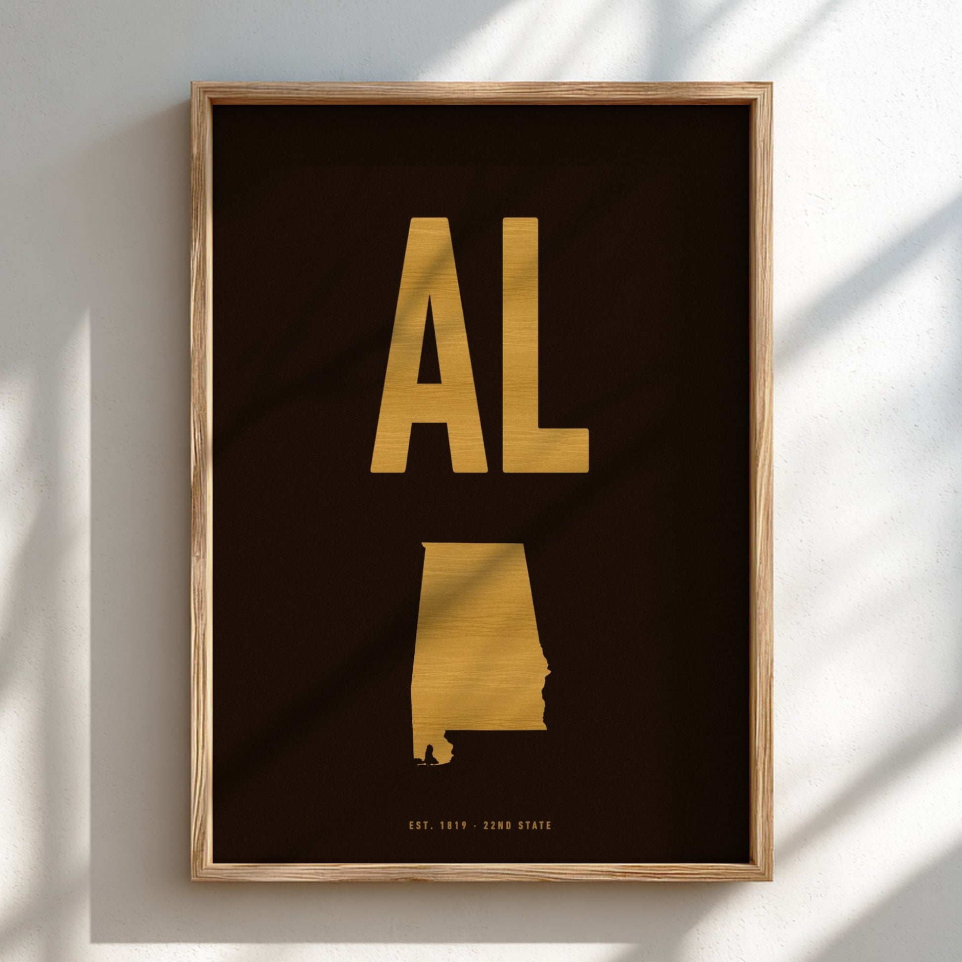 Framed artwork with gold state outline and 'AL' on a black background