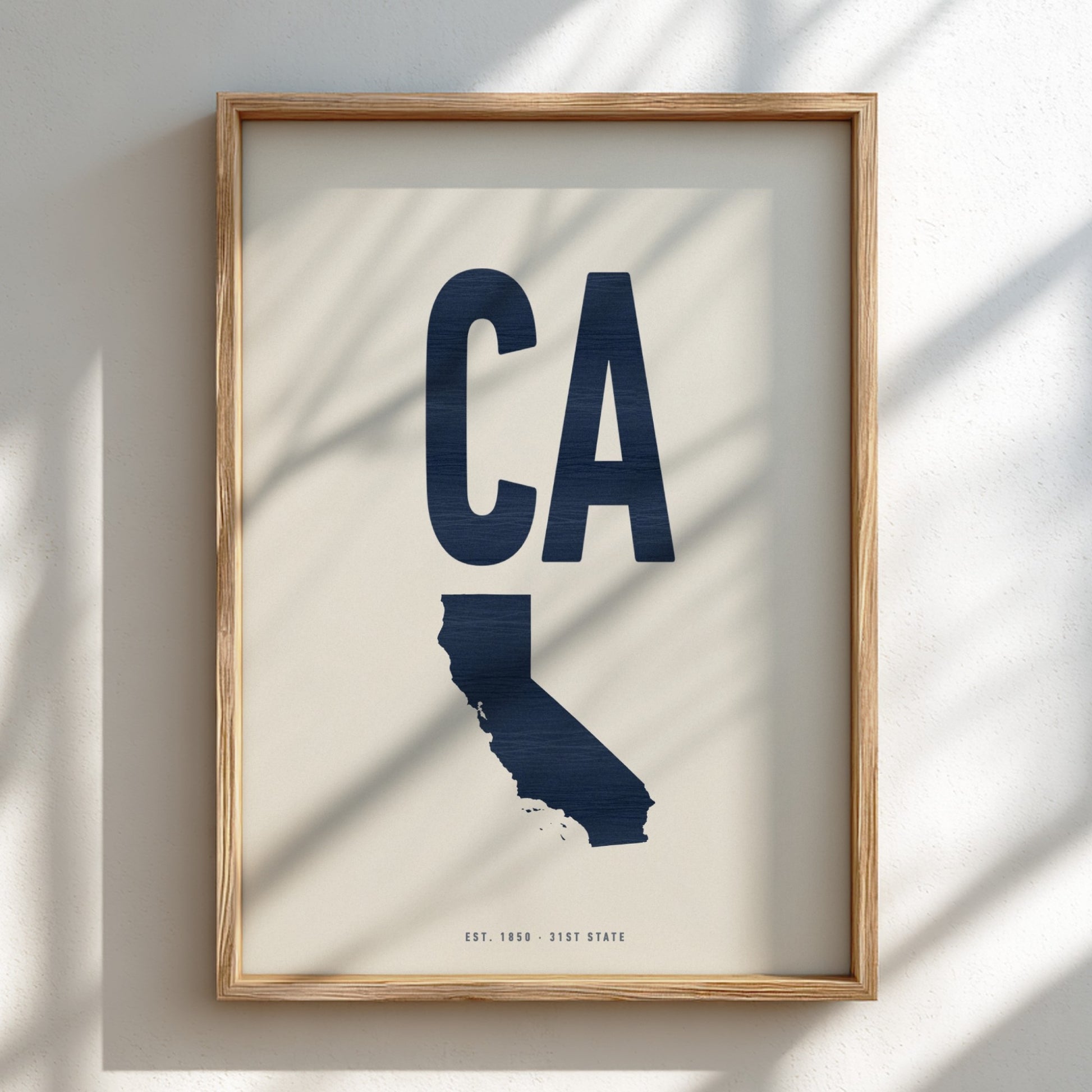 Framed artwork of a blue 'CA' state outline on a beige background