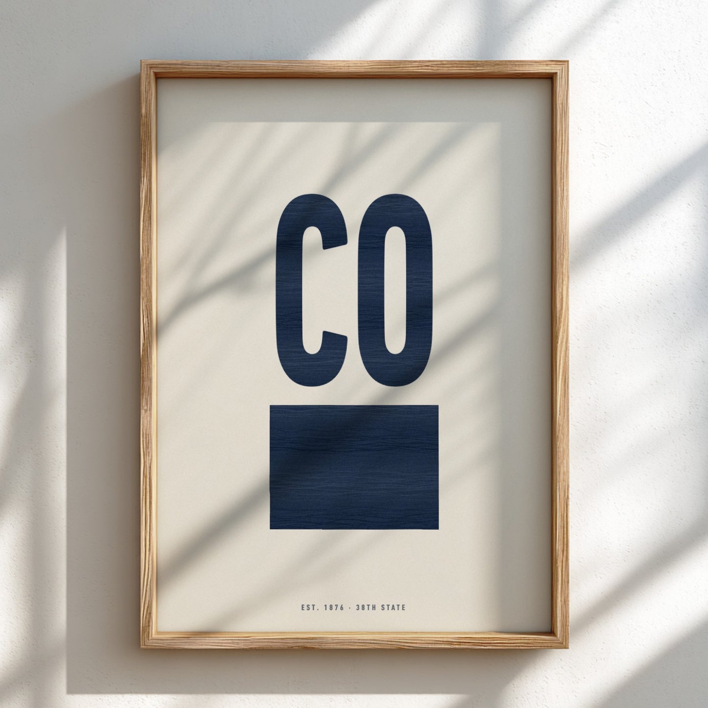 Framed artwork with 'CO' in navy on a light background