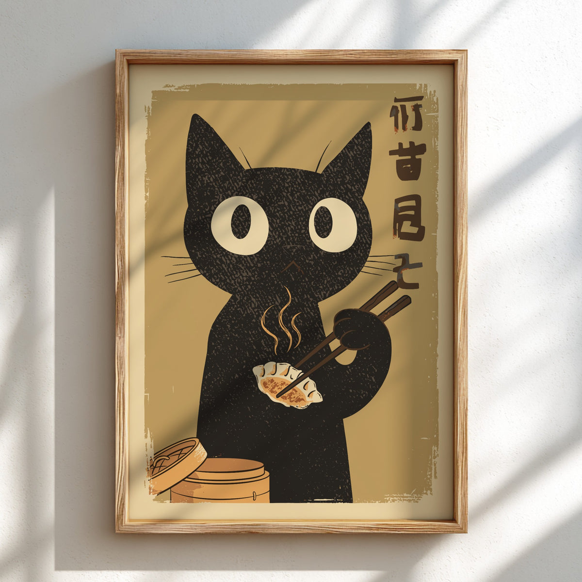 A framed art print featuring a black cat with large white eyes holding chopsticks and a dumpling, set against a warm beige background with vertical black characters on the right. The print is housed in a light wood frame and displayed on a white wall with soft window shadow patterns.