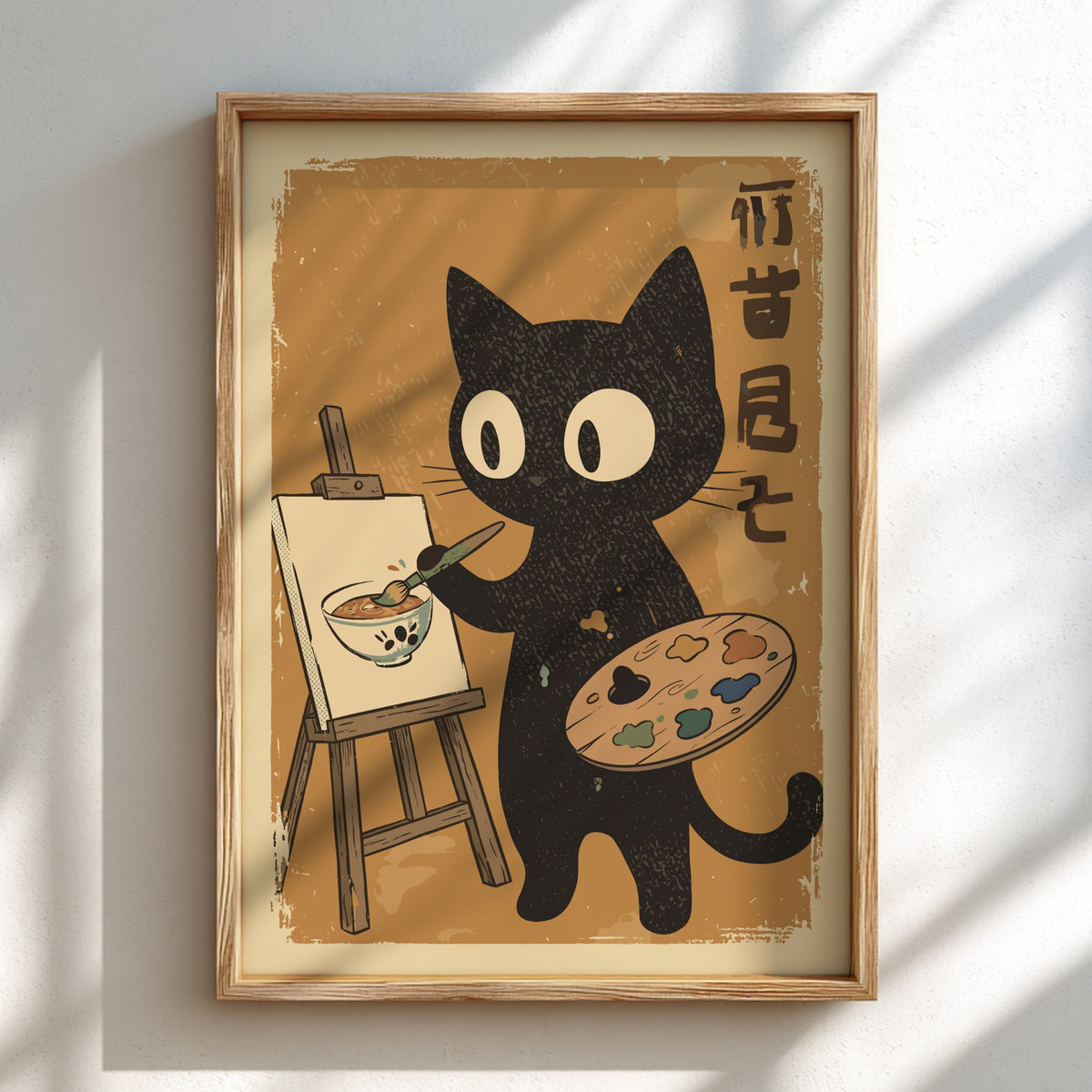 A framed art print featuring a cute black cat painting on an easel, displayed on a light wall with soft window shadows.
