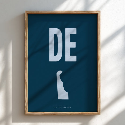 Framed poster with 'DE' on a blue background, featuring a silhouette of a state.
