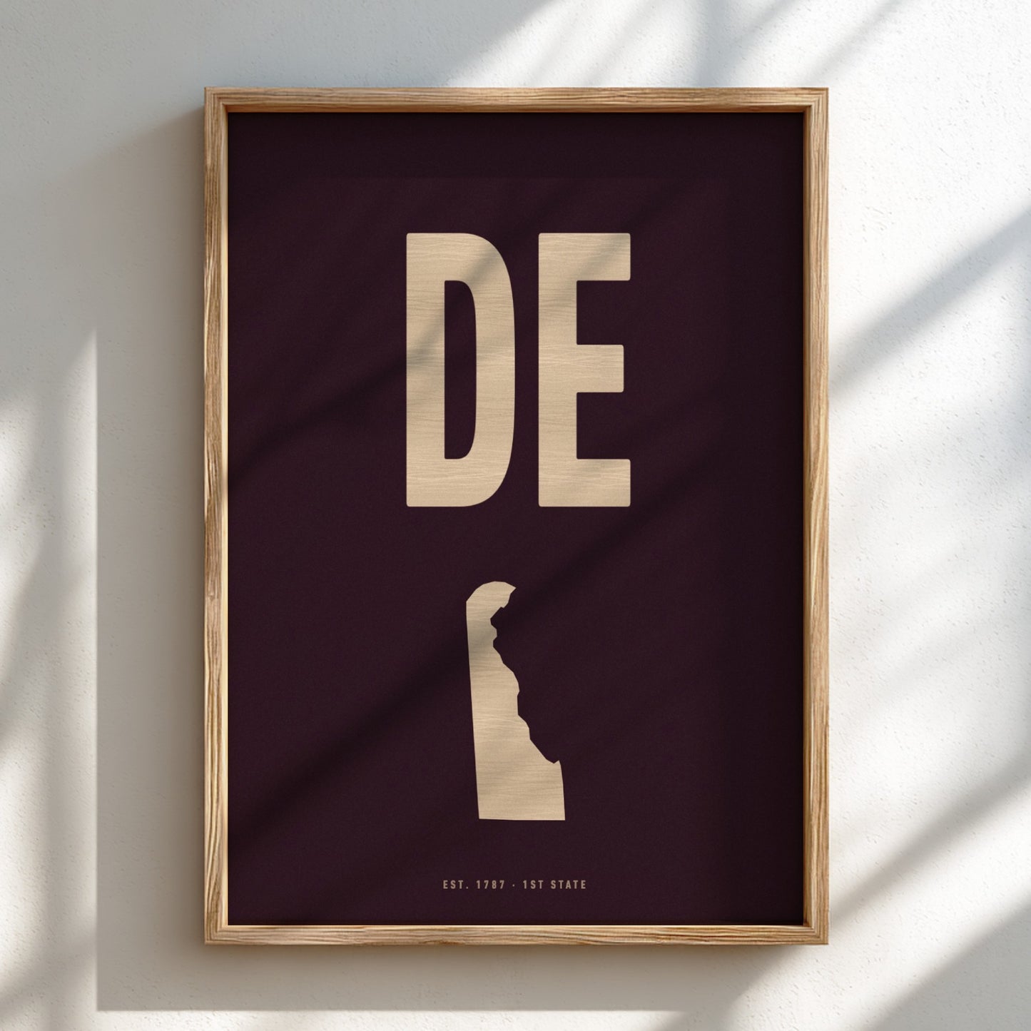 Framed artwork with 'DE' and silhouette of a state on a dark background
