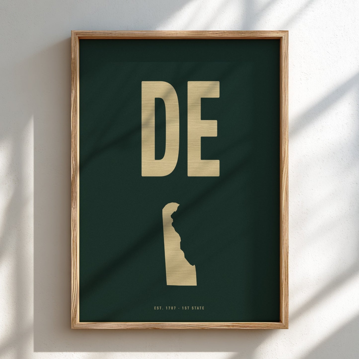 Framed artwork with 'DE' in gold on a dark green background
