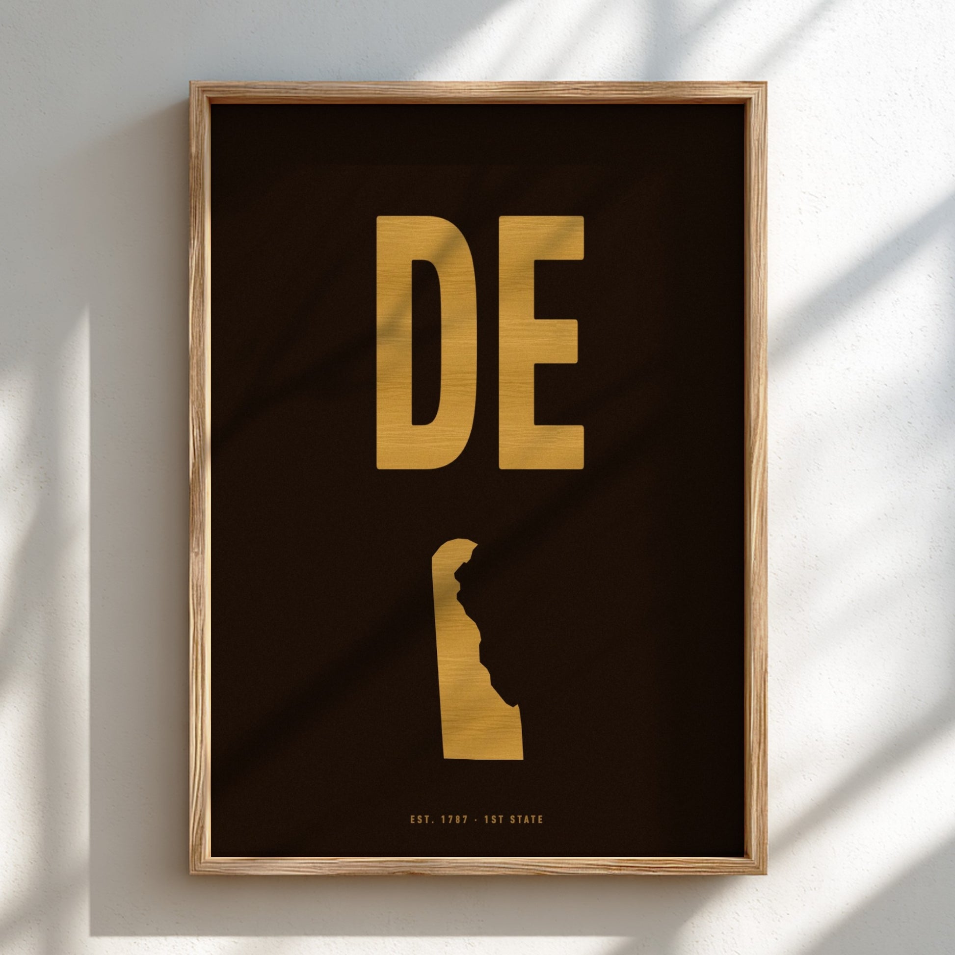 Framed artwork with 'DE' in gold on a dark background