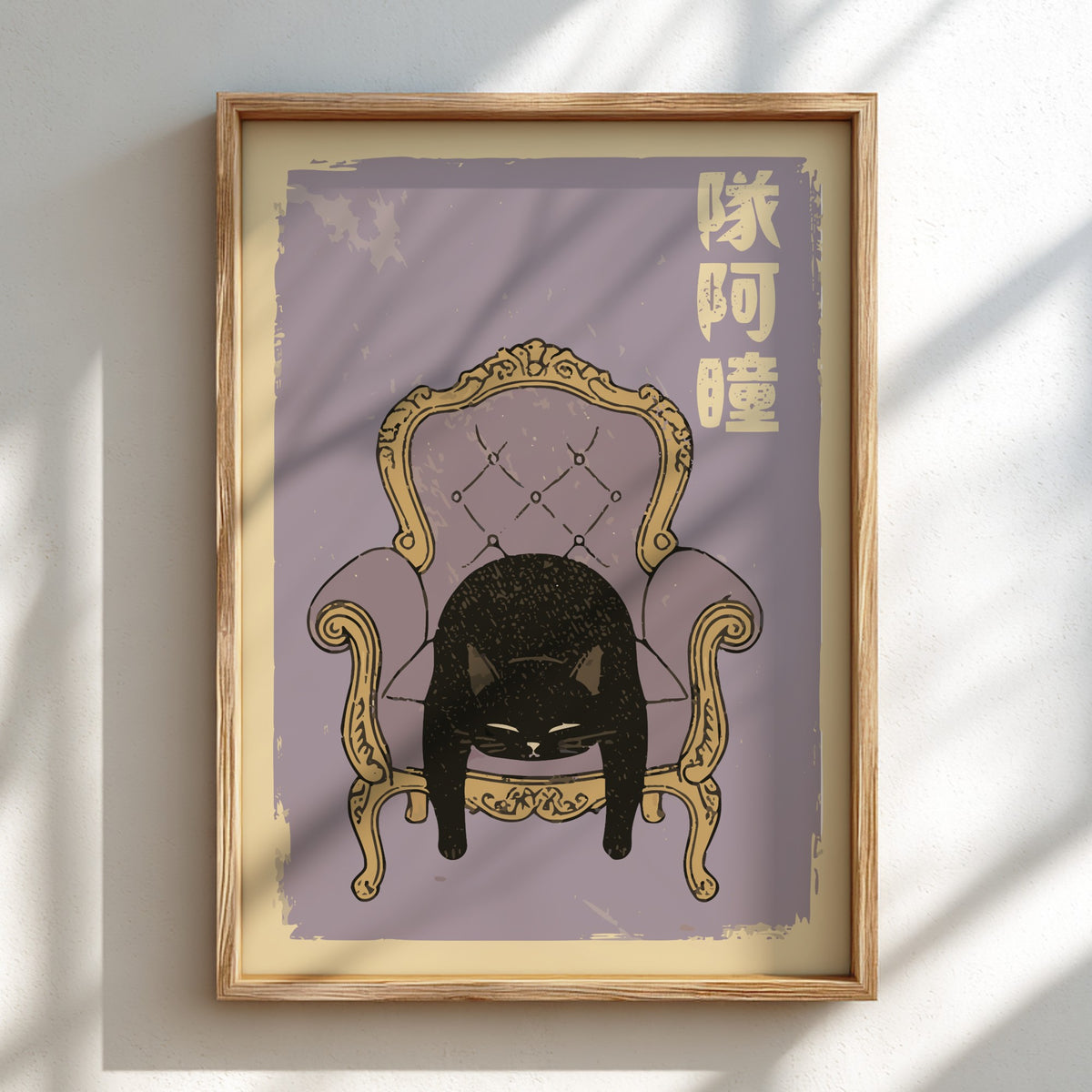A framed art print featuring a black cat curled up inside an ornate gold armchair on a muted lavender background, with gold Chinese characters in the upper right. The print is housed in a light natural wood frame and is mounted on a white wall with soft window shadow patterns.