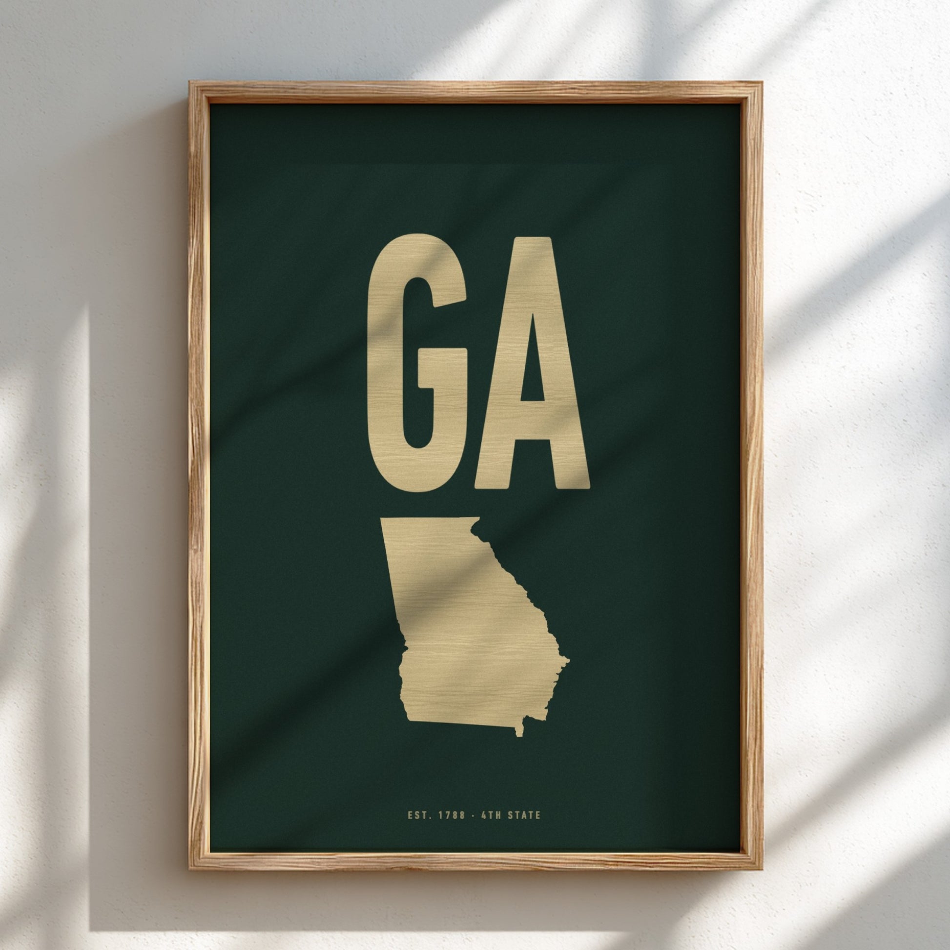 Framed artwork of a gold map of Georgia on a dark green background