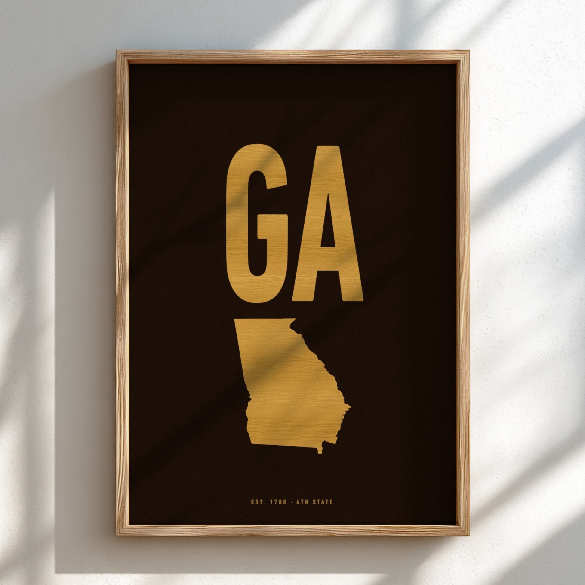 Framed artwork with gold 'GA' and state outline on black background