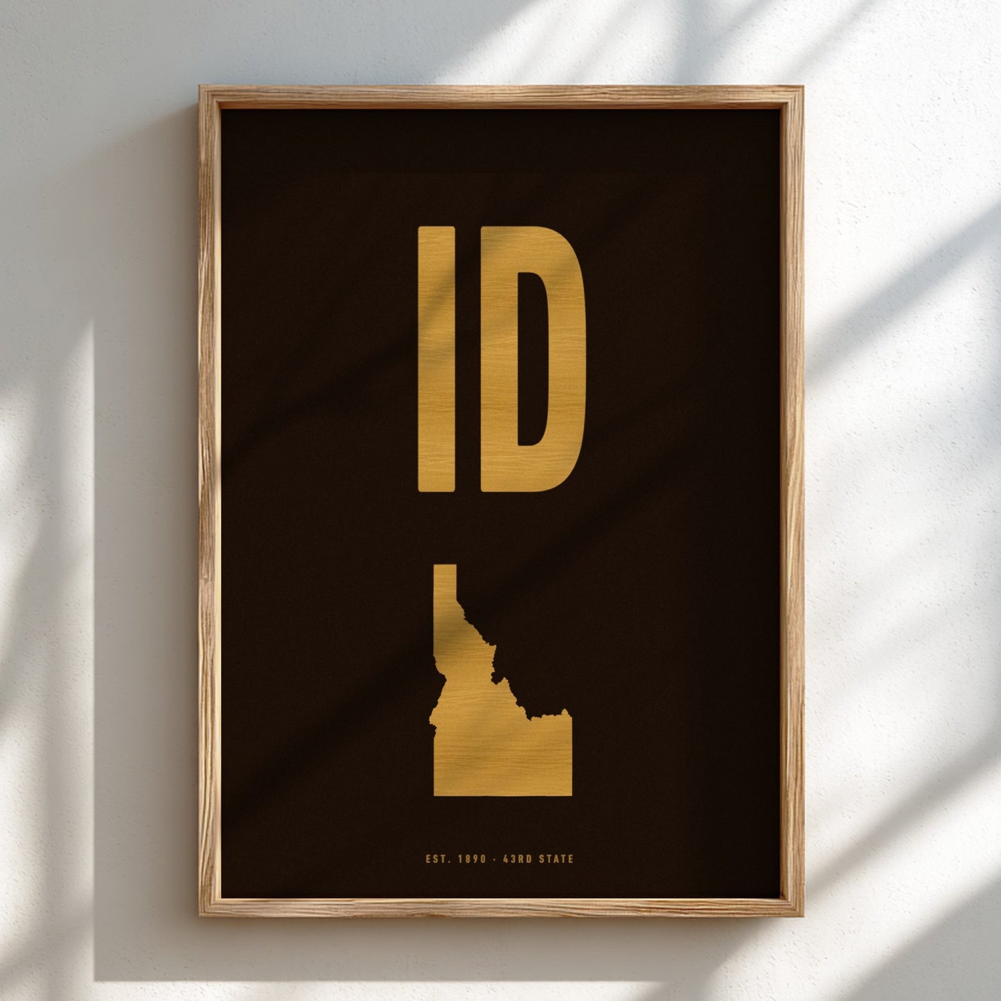 Framed artwork of Idaho's state shape in gold on a dark background