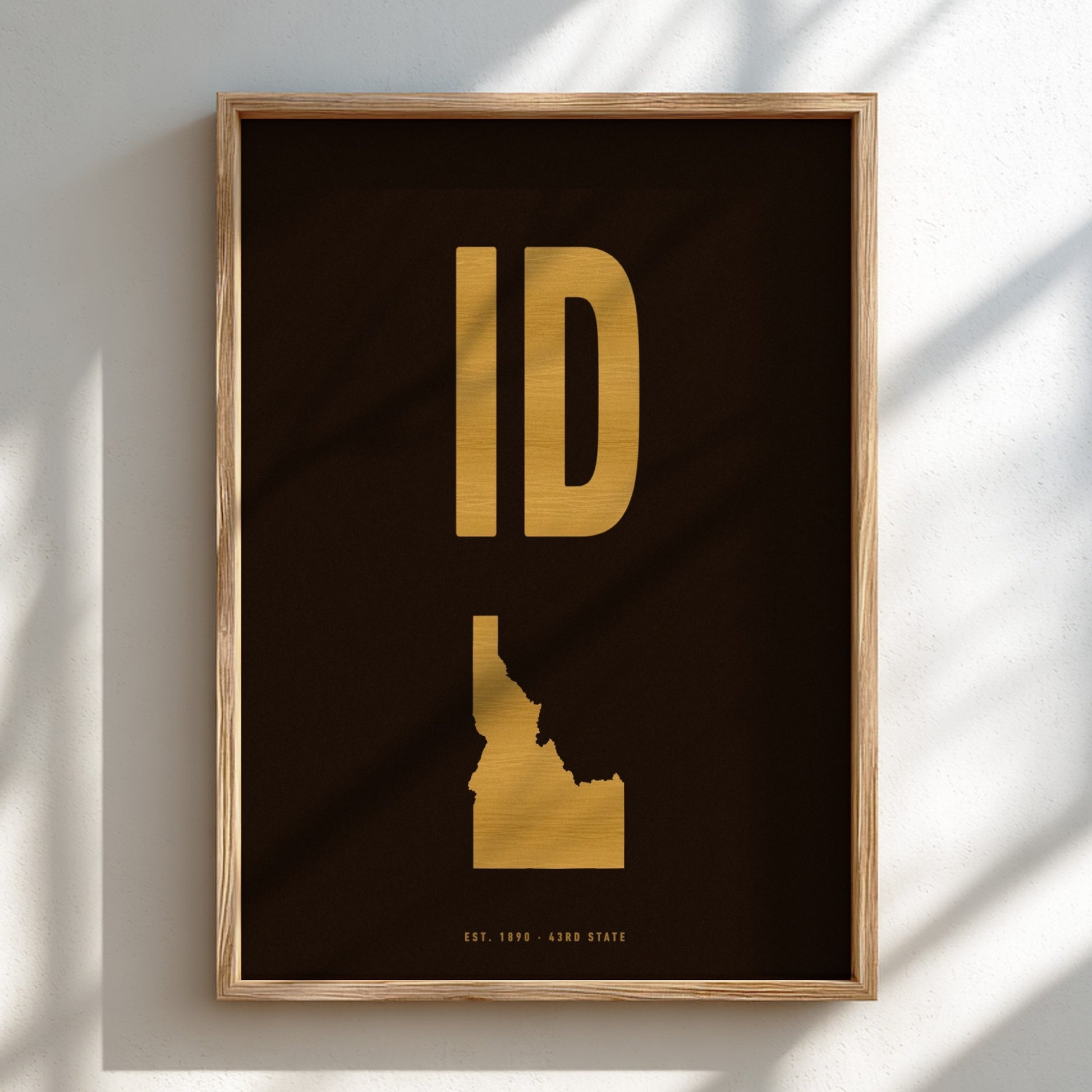 Framed artwork of Idaho's state shape in gold on a dark background