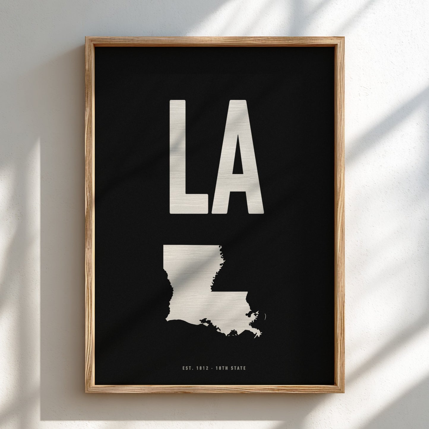 Framed artwork with 'LA' and a map of Louisiana on a black background