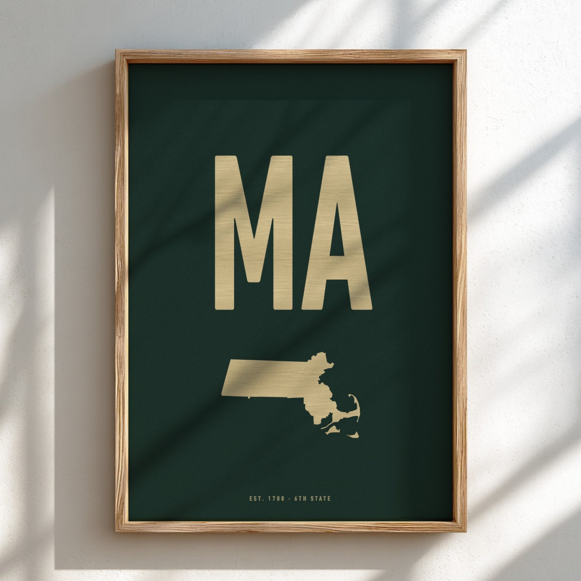 Framed poster with gold 'MA' and state outline on a dark green background