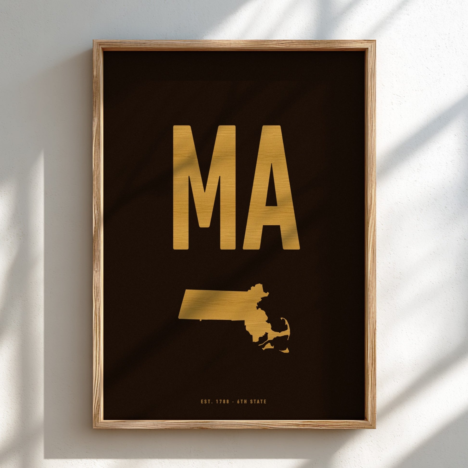 Framed artwork with gold 'MA' and state outline on black background