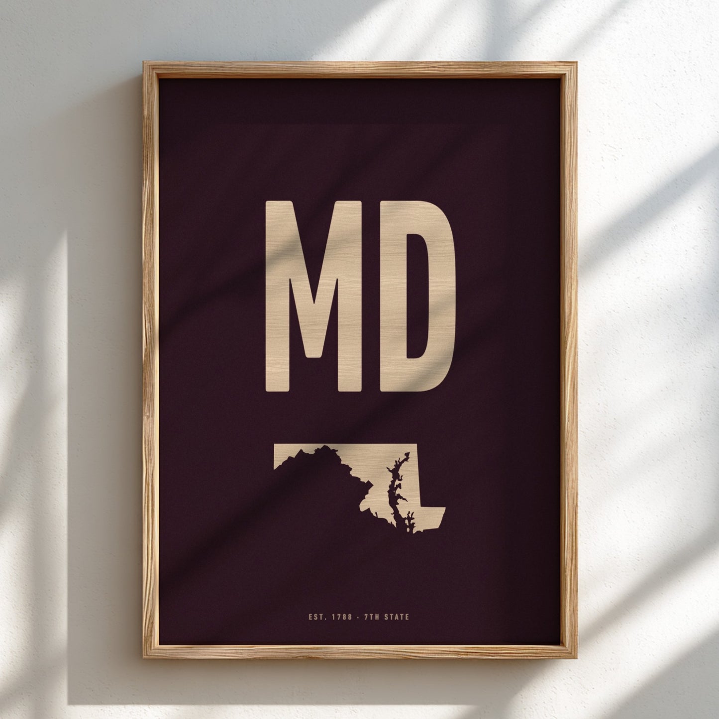 Framed artwork with 'MD' and silhouette of Maryland on a dark background