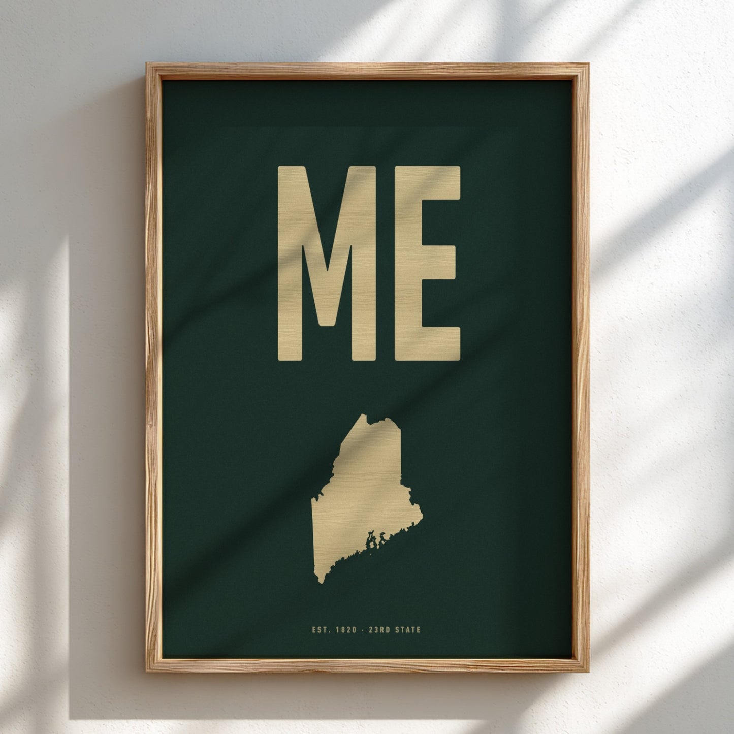 Framed artwork with 'ME' and a map of Maine on a dark green background