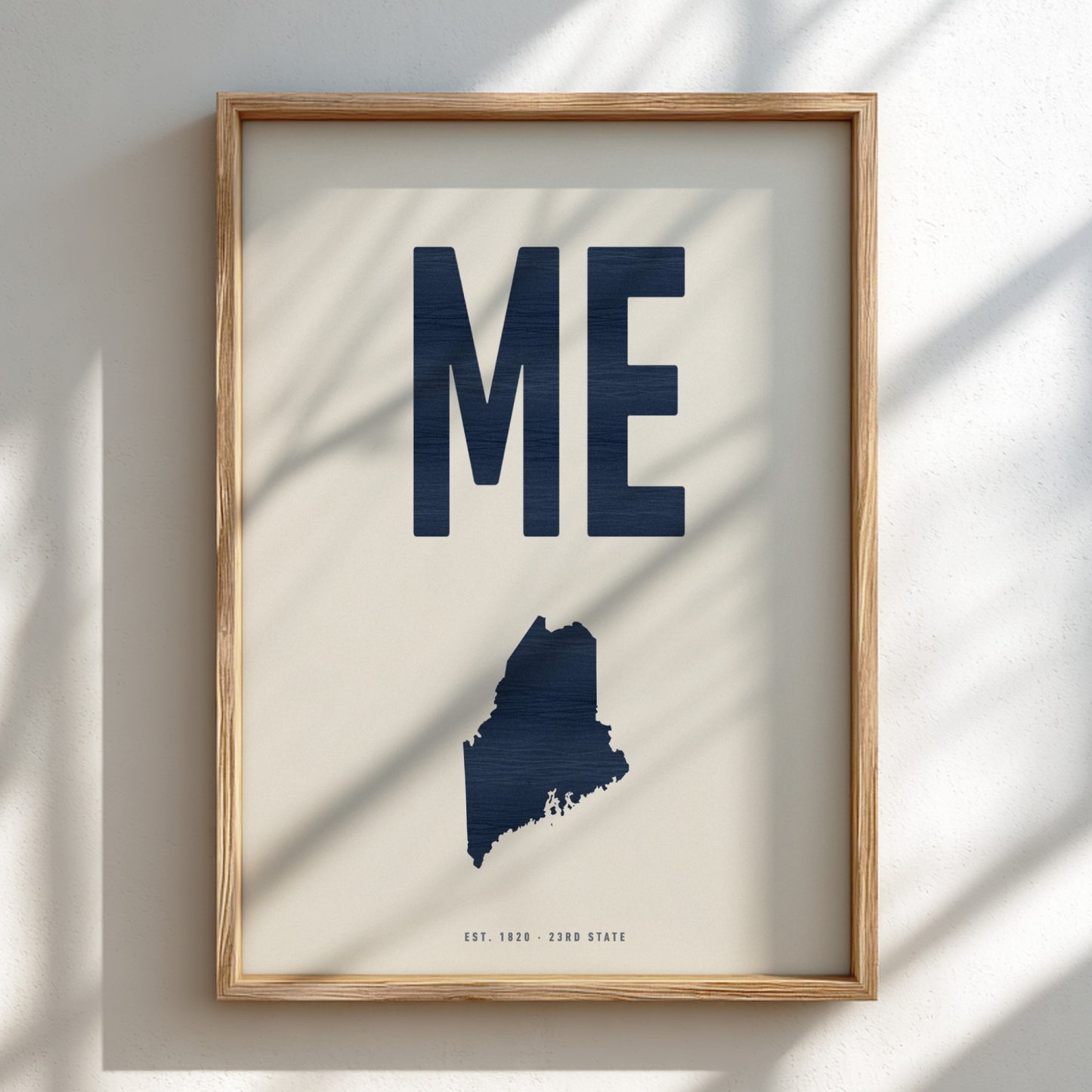Framed artwork with 'ME' and a map of Maine on a light background
