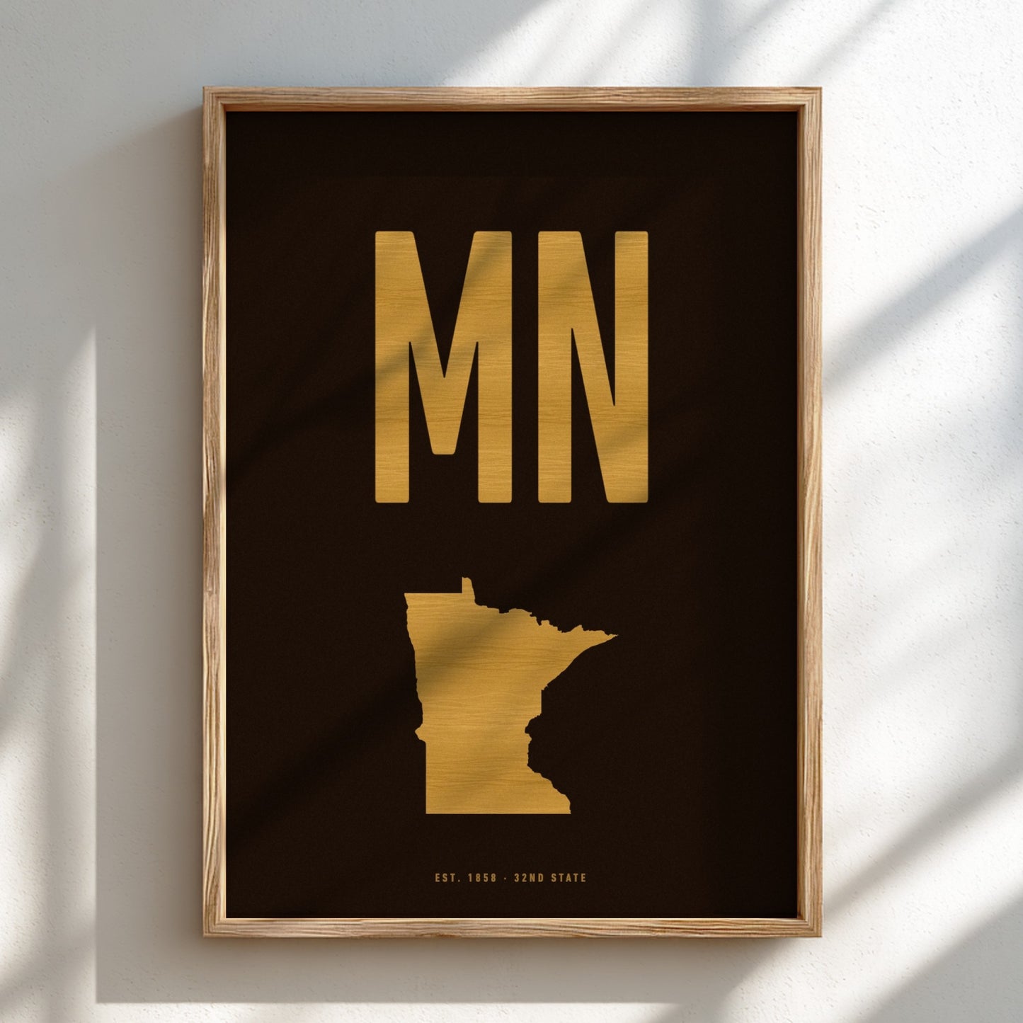 Framed artwork with gold 'MN' and state outline on a black background
