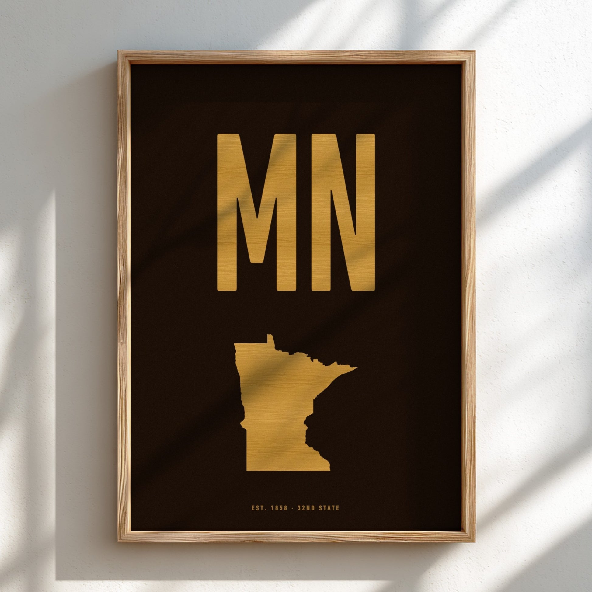 Framed artwork with gold 'MN' and state outline on a black background