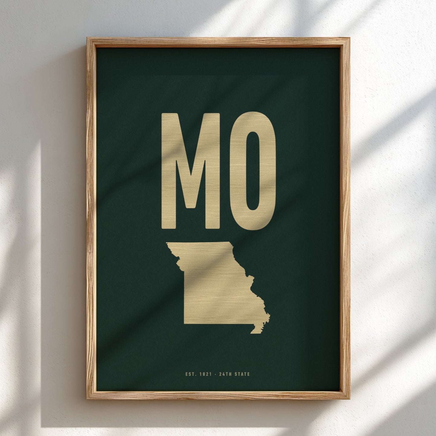Framed artwork with gold 'MO' and state outline on a dark green background