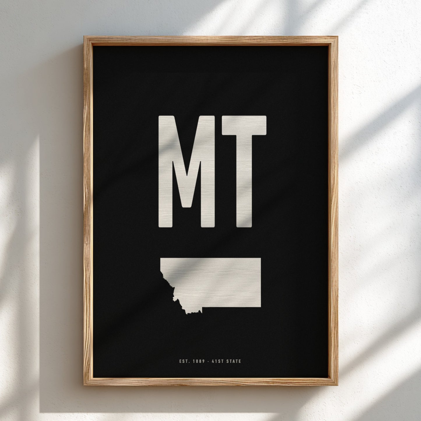 Framed poster with 'MT' and a map outline on a black background