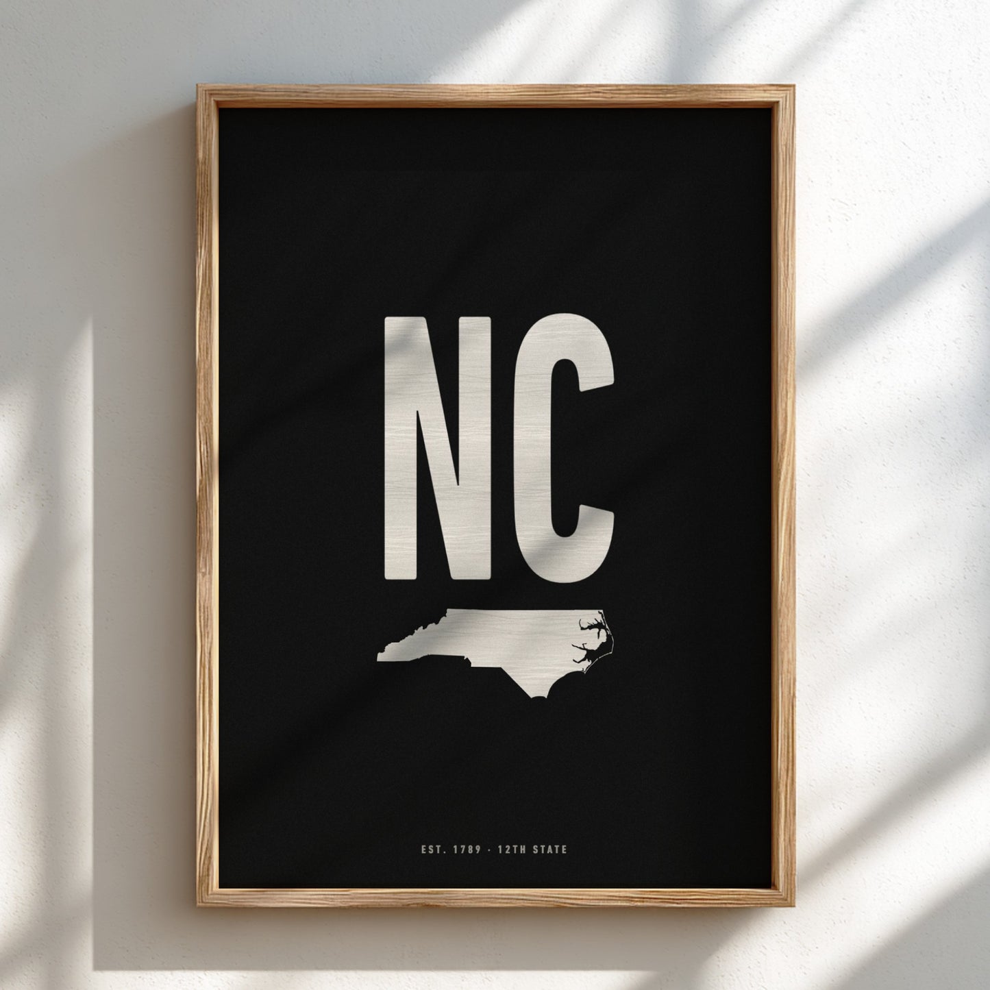 Framed poster with 'NC' and a map of North Carolina on a black background