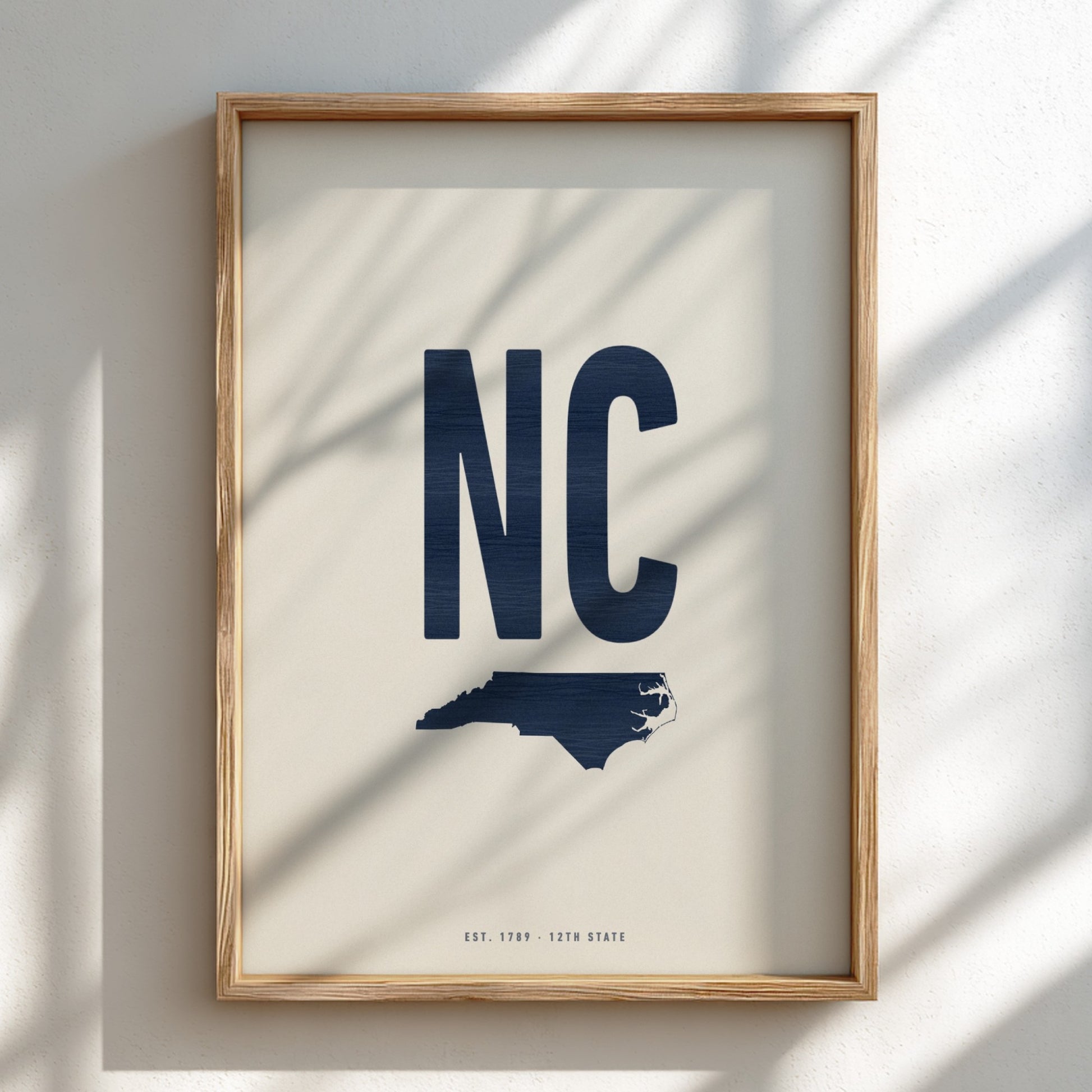 Framed artwork with 'NC' and a map of North Carolina on a beige background