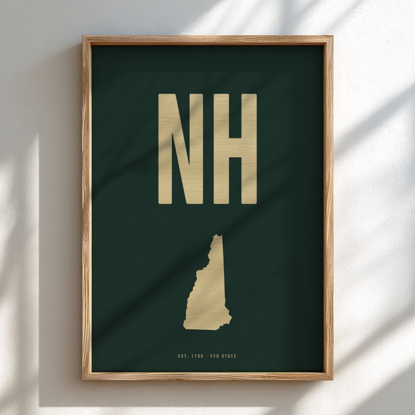 Framed artwork with 'NH' and a map of New Hampshire on a dark green background