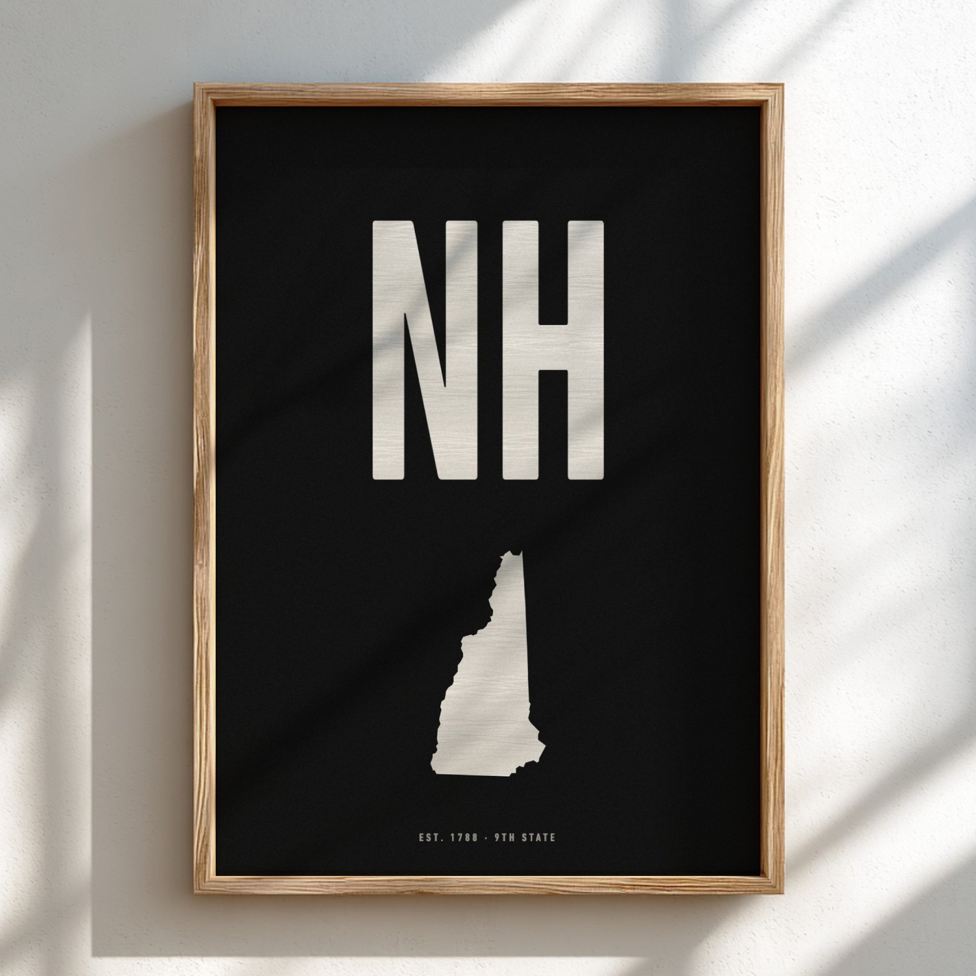 Framed poster with 'NH' and a map of New Hampshire on a black background