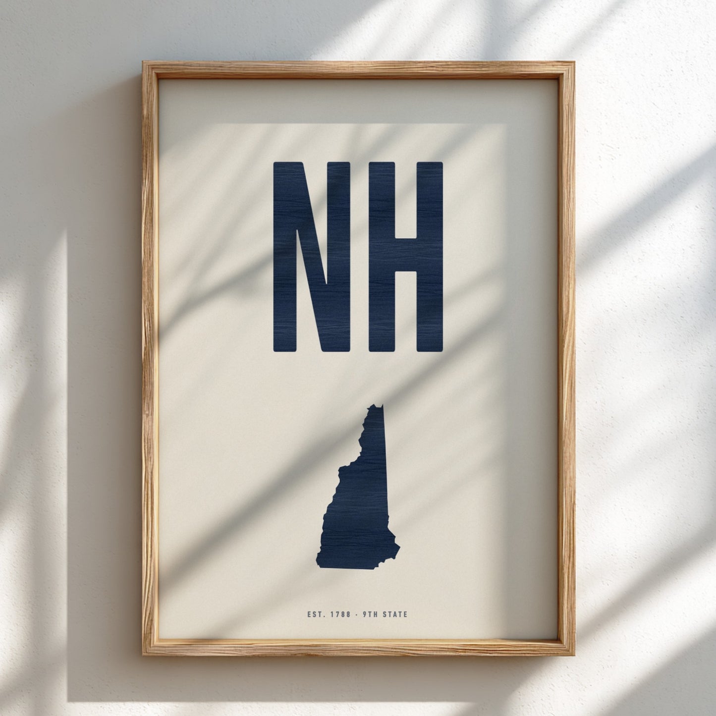 Framed artwork with 'NH' and a map of New Hampshire on a light background