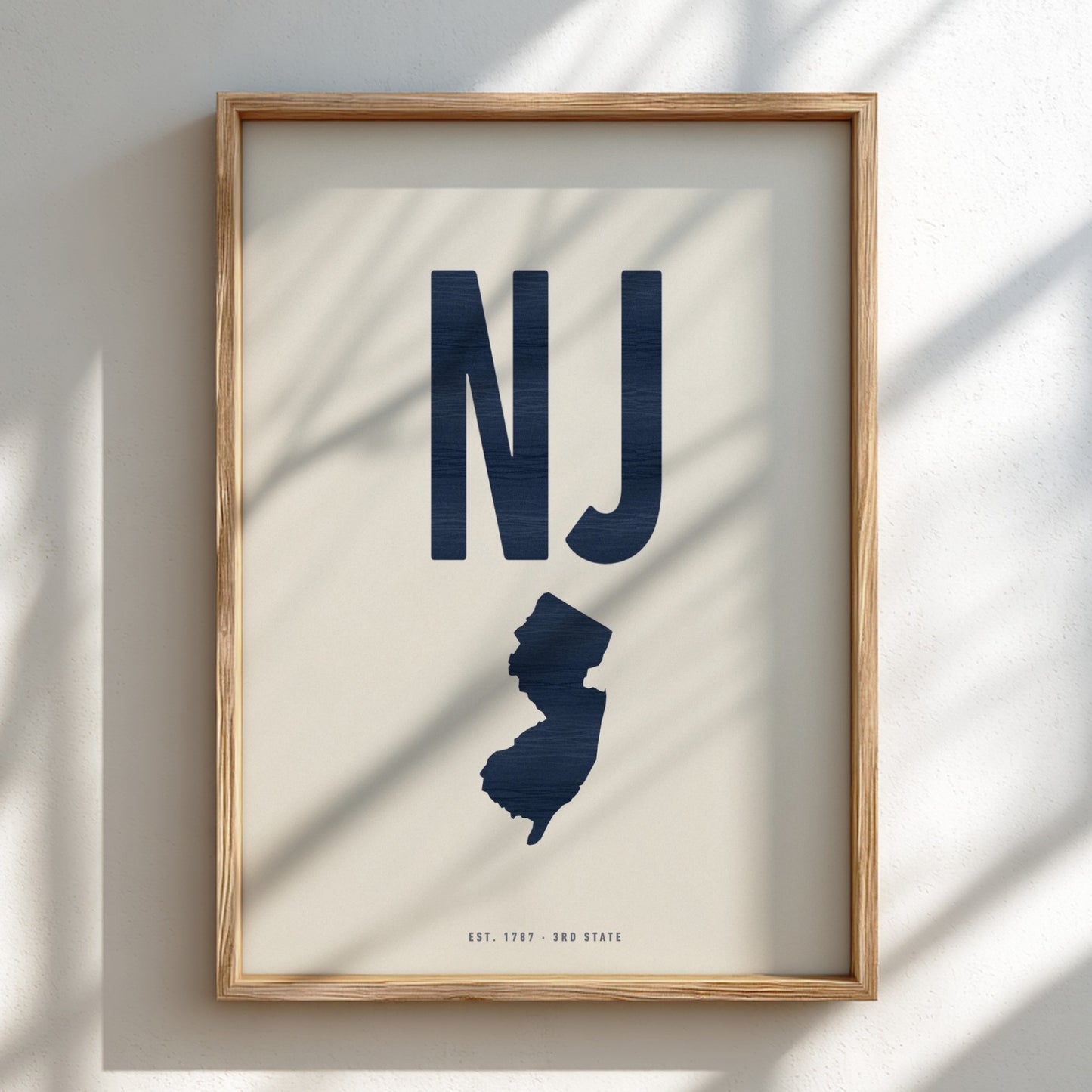Framed artwork with 'NJ' and silhouette of New Jersey on a light background