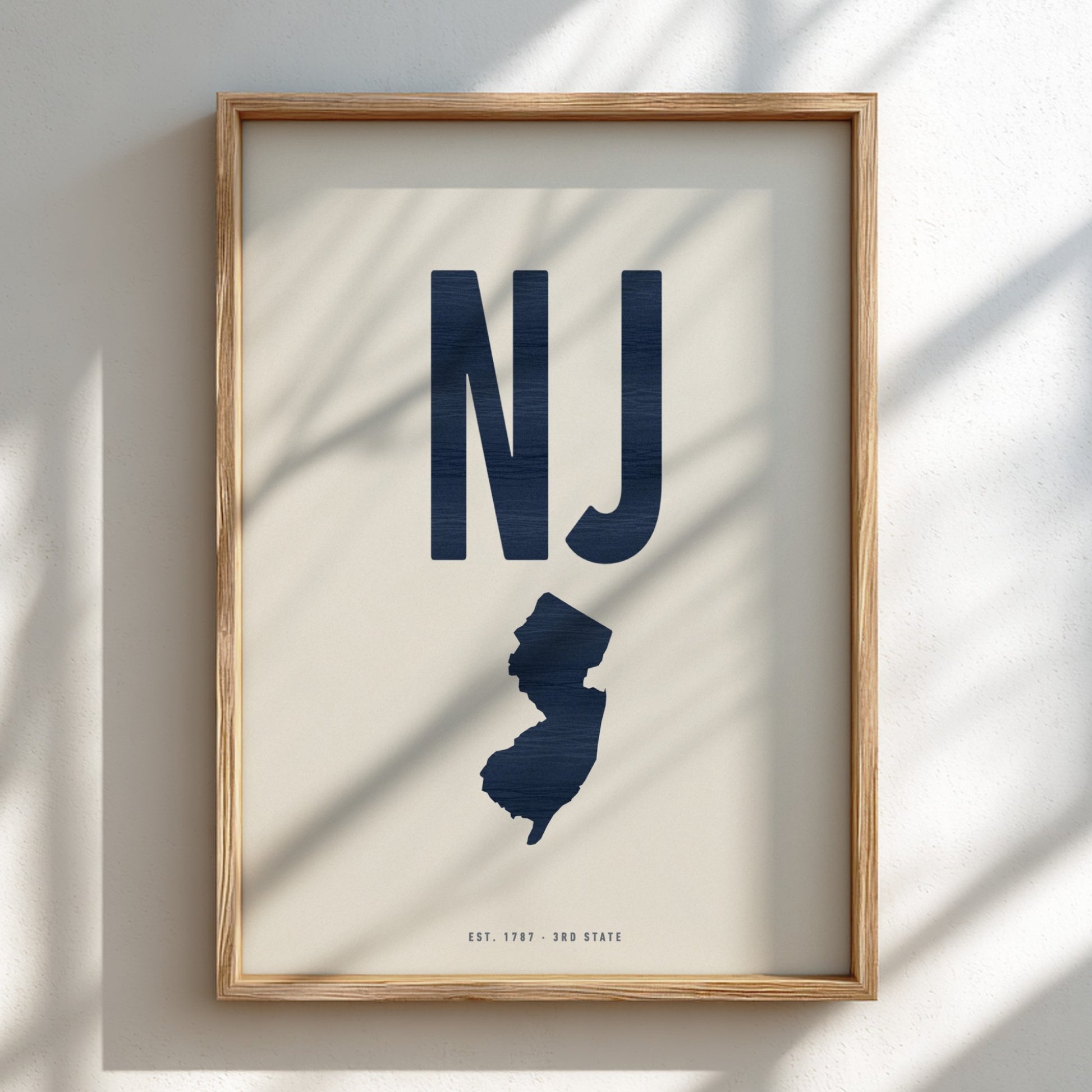 Framed artwork with 'NJ' and silhouette of New Jersey on a light background
