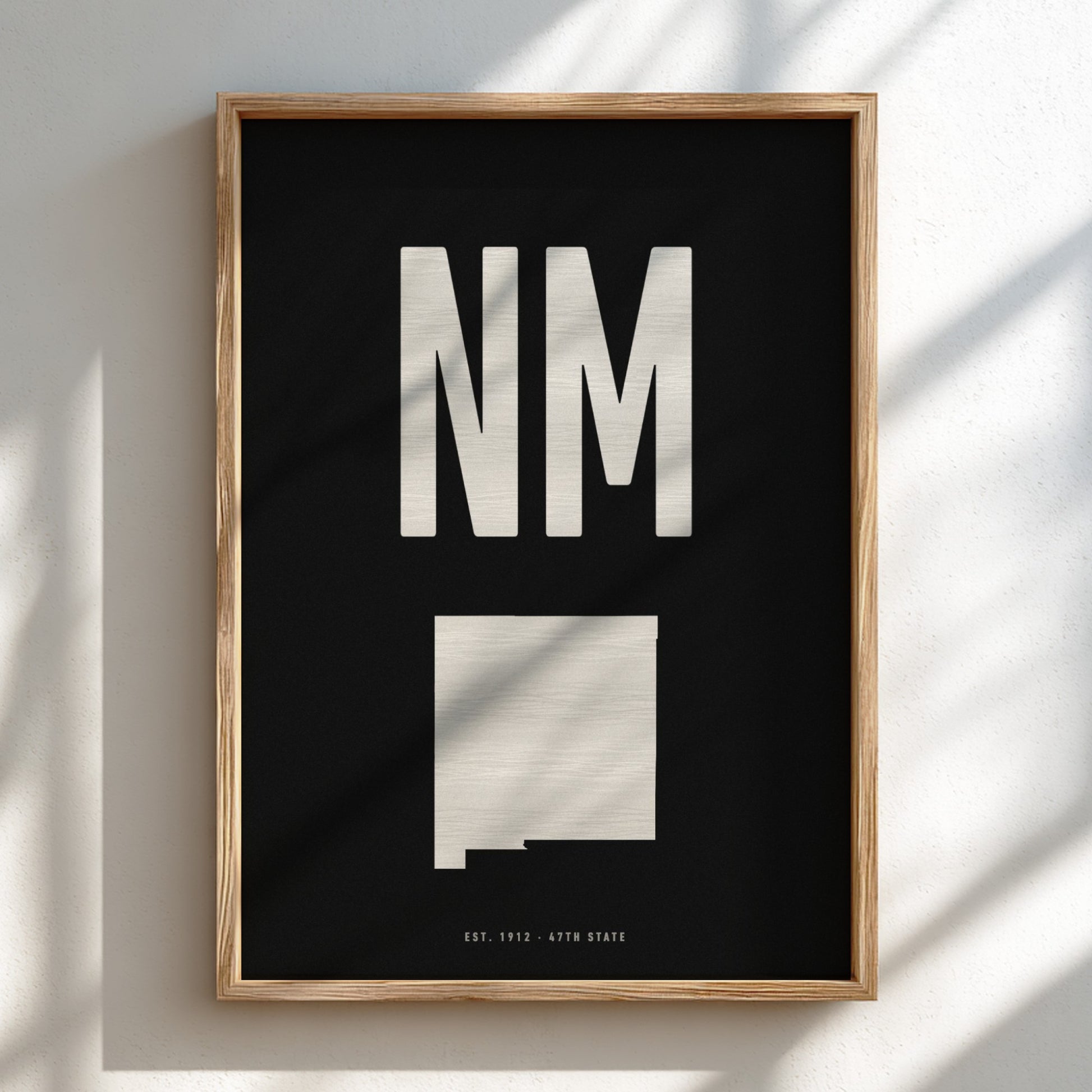 Framed artwork with 'NM' and a map of New Mexico on a black background