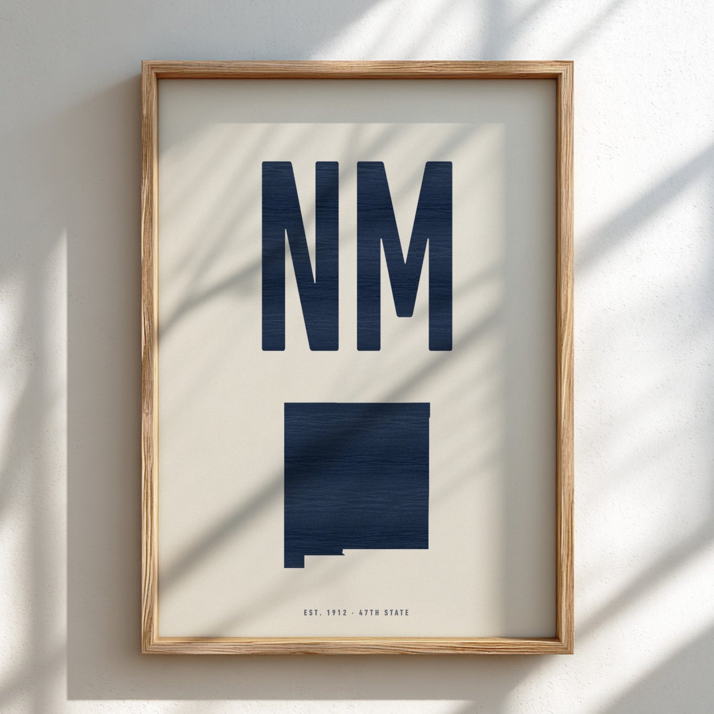 Framed artwork with 'NM' and a map of New Mexico on a light background