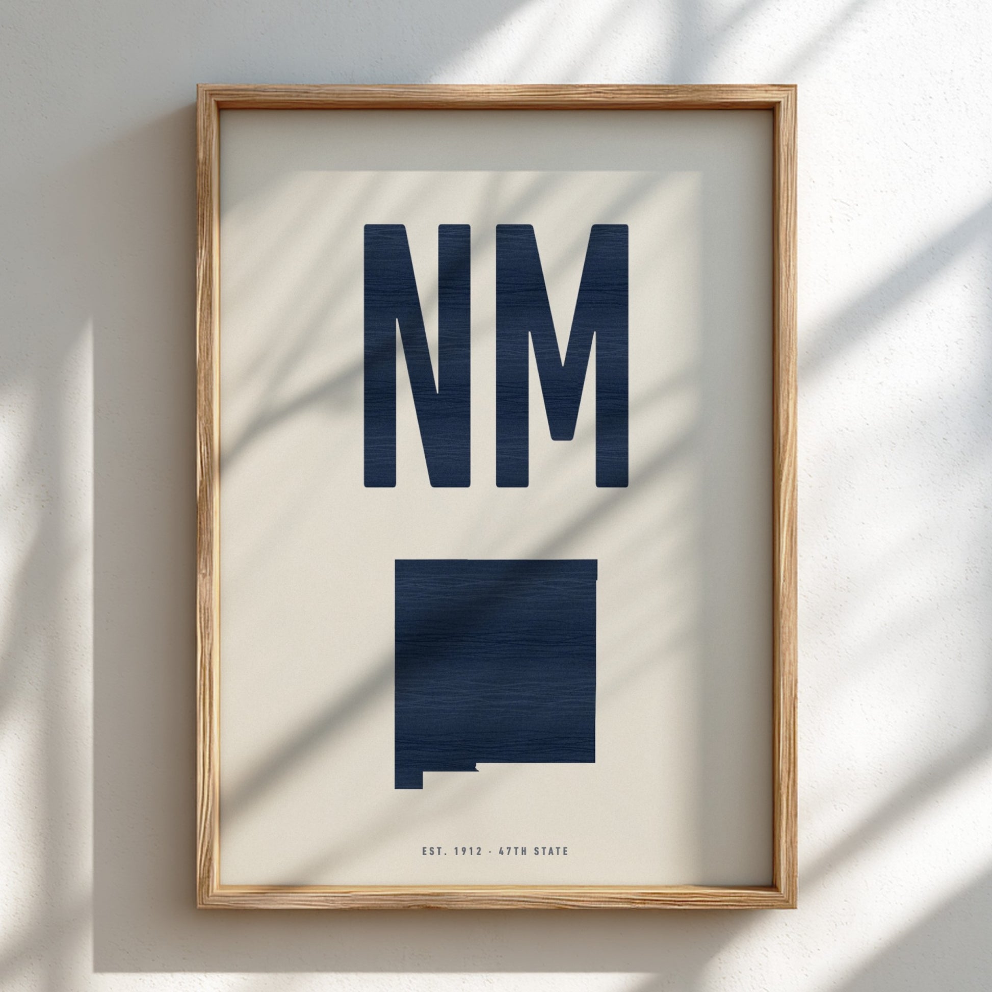 Framed artwork with 'NM' and a map of New Mexico on a light background
