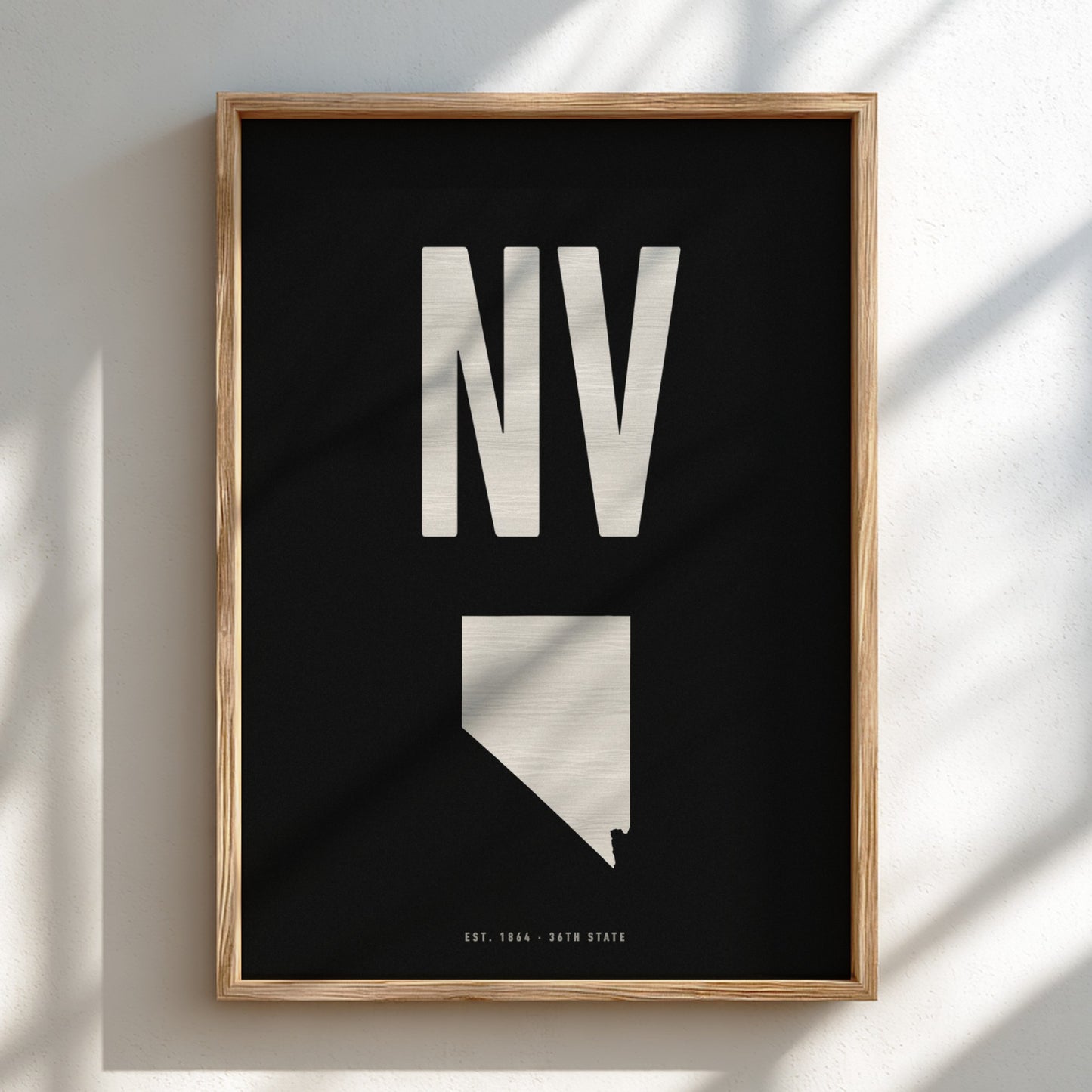 Framed artwork with 'NV' and a map outline of Nevada on a black background.