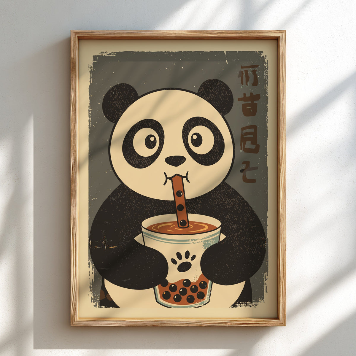 A framed art print featuring a cute cartoon panda holding a cup of bubble tea, displayed on a light wall with soft diagonal shadows.