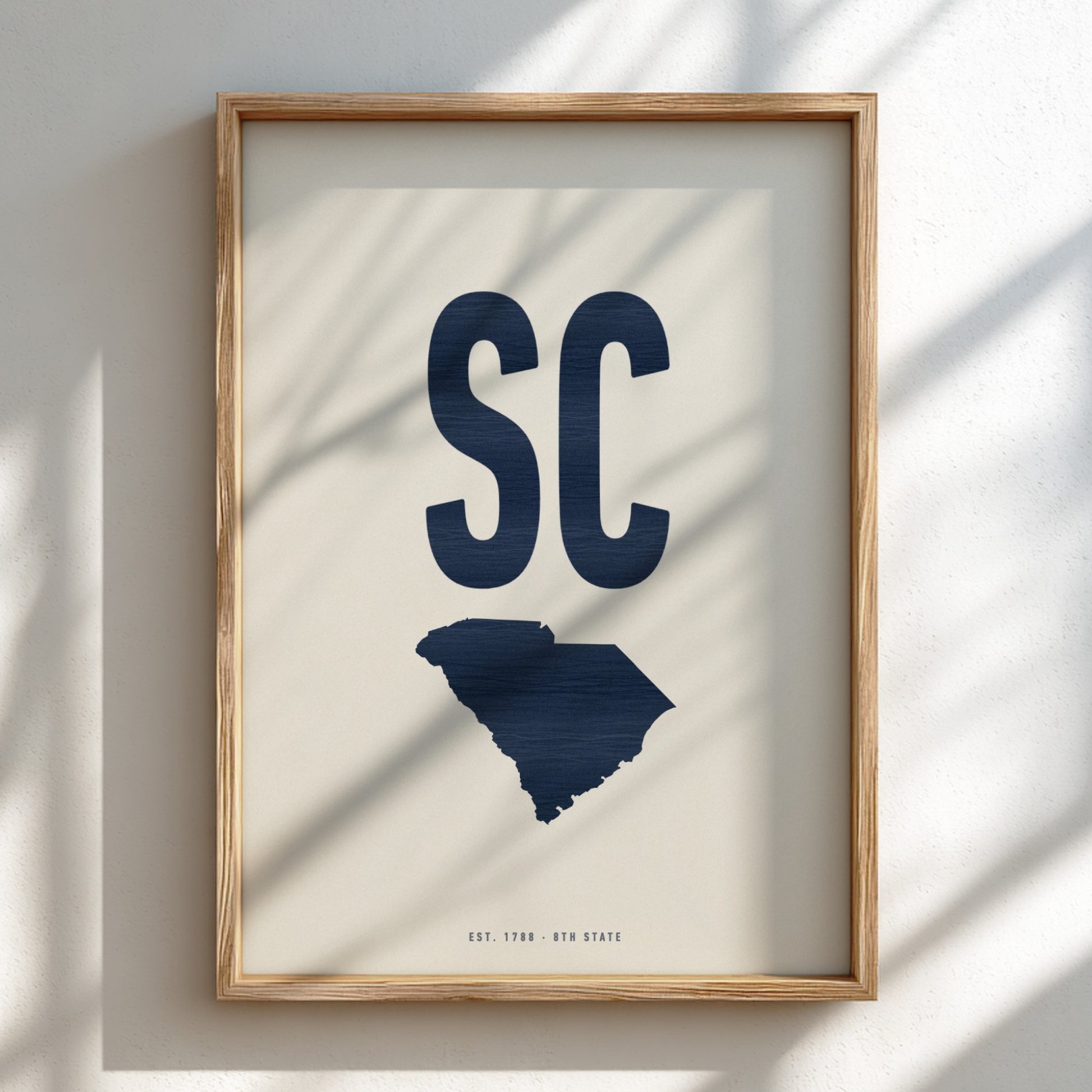 Framed artwork with 'SC' and a map of South Carolina on a light background