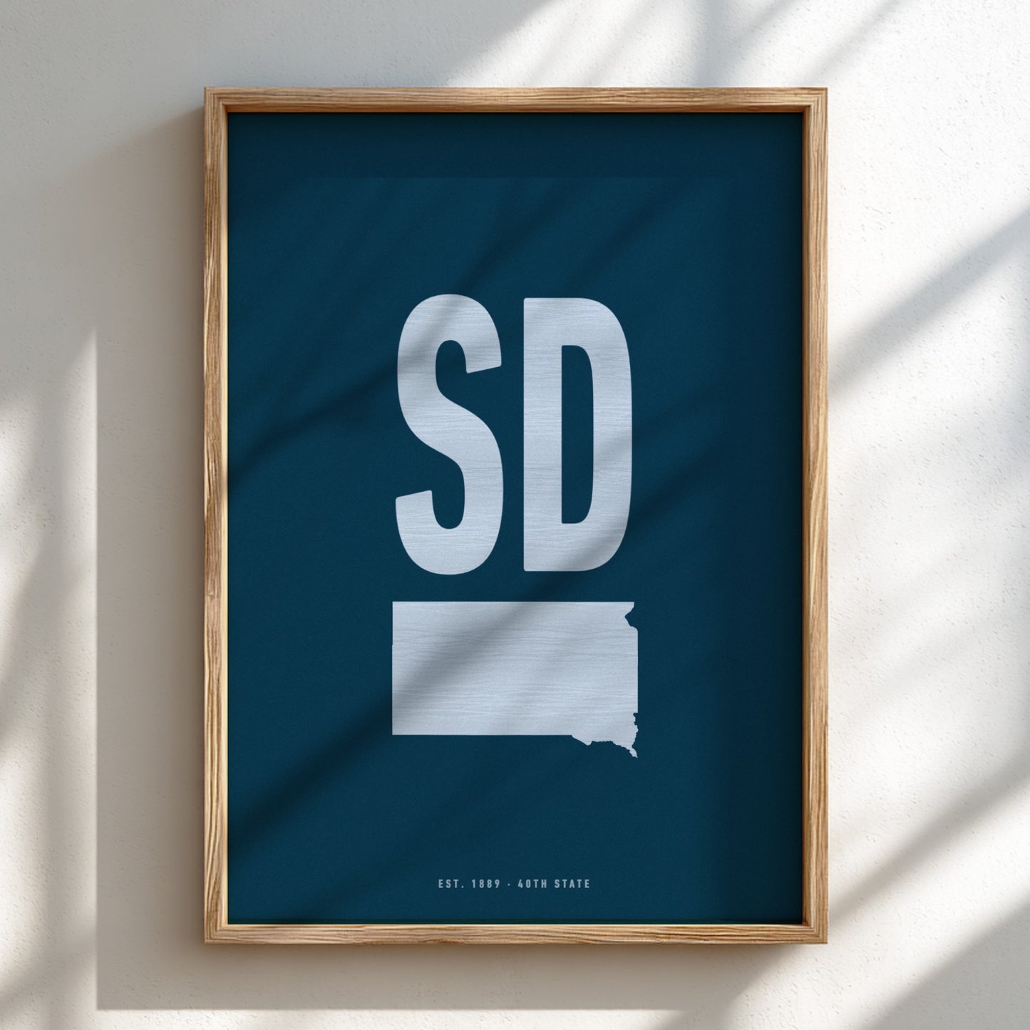 Framed poster with 'SD' and outline of South Dakota on a blue background