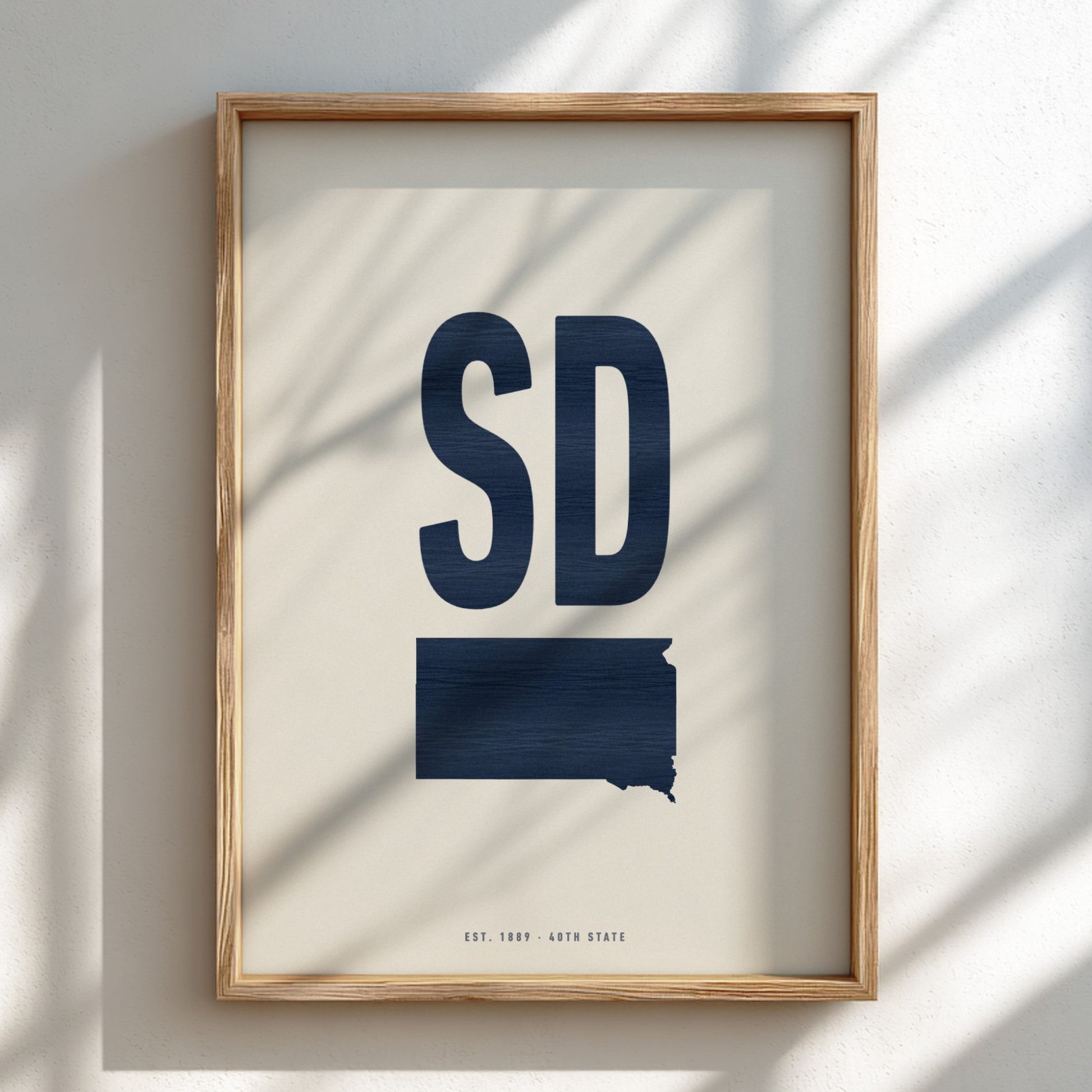 Framed artwork with 'SD' and a map of South Dakota on a light background