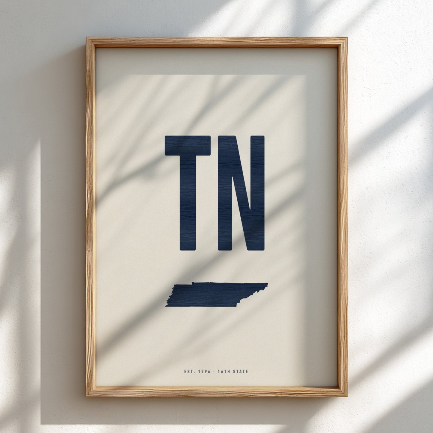 Framed artwork with 'TN' in blue on a beige background