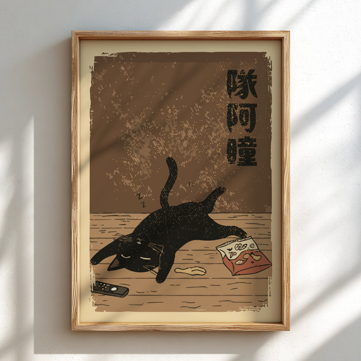 A framed art print featuring a black cat stretching on a wooden floor with Japanese text, displayed on a white wall with soft window shadow patterns.